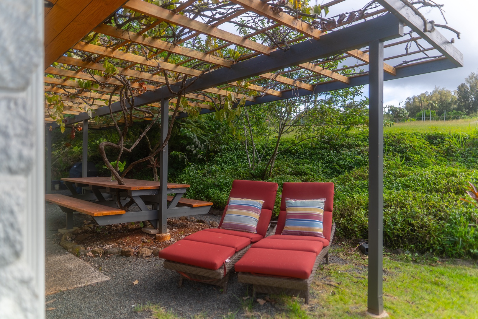 Haleiwa Vacation Rentals, Hale Mahina - Lounge under the pergola on cushioned chairs, tucked into a quiet garden setting.