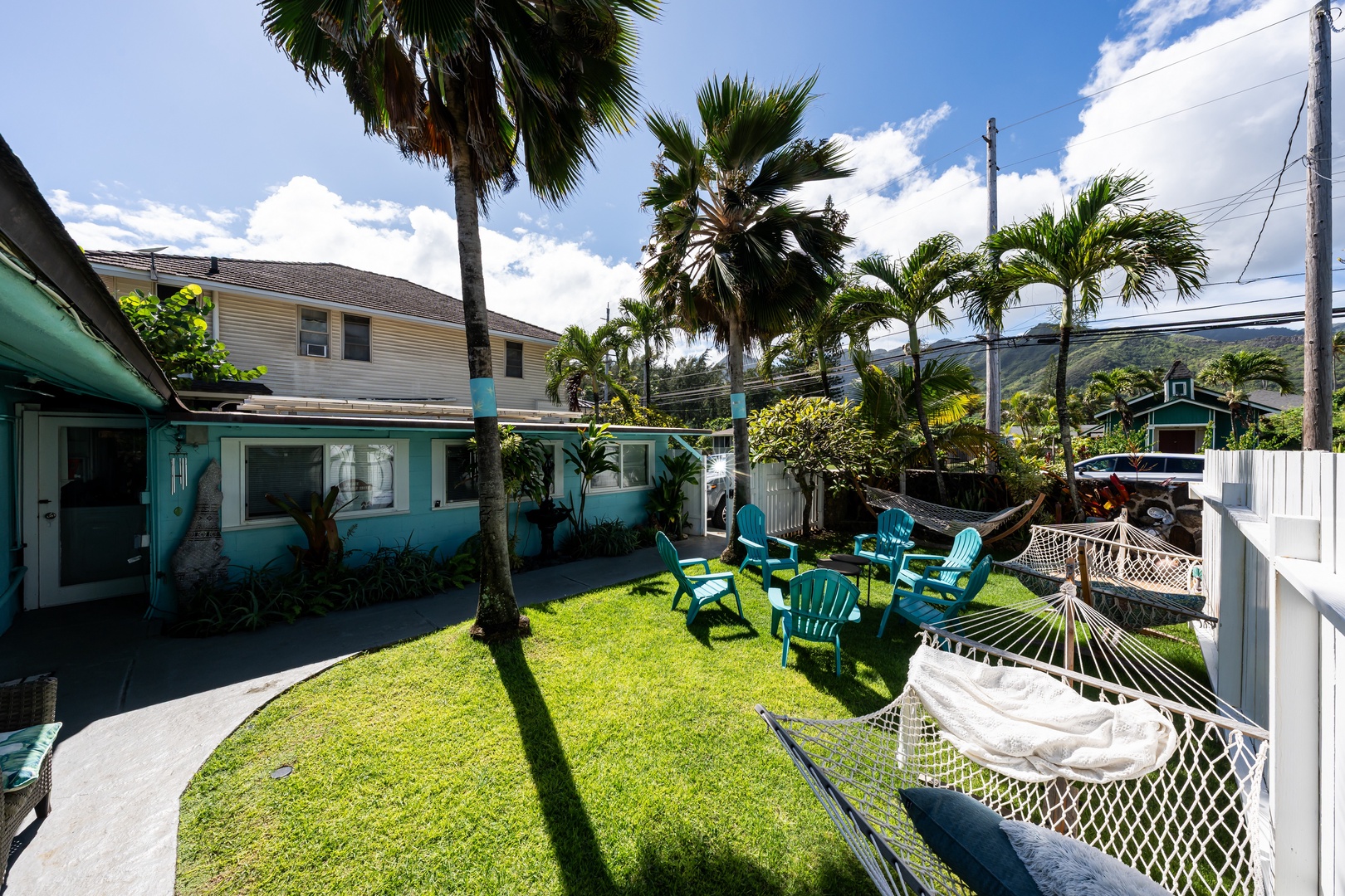 Hauula Vacation Rentals, Private Beach Paradise - Lush green lawn with palm trees, Adirondack chairs, and a hammock for relaxing afternoons.