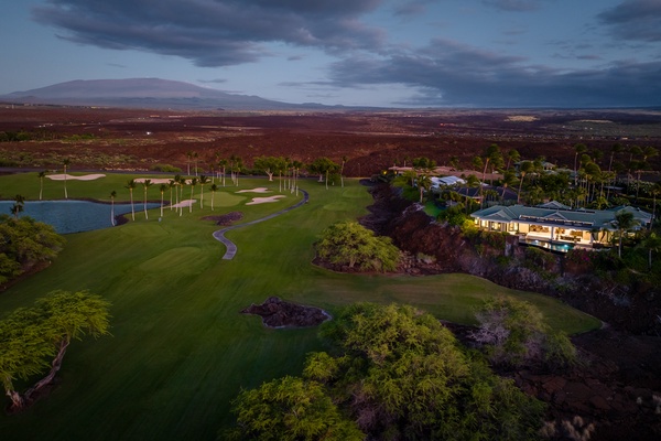 Kamuela Vacation Rentals, Champion Ridge 22 & 24 - Aerial view of a scenic golf course at dusk, with lush greenery and a luxurious home.