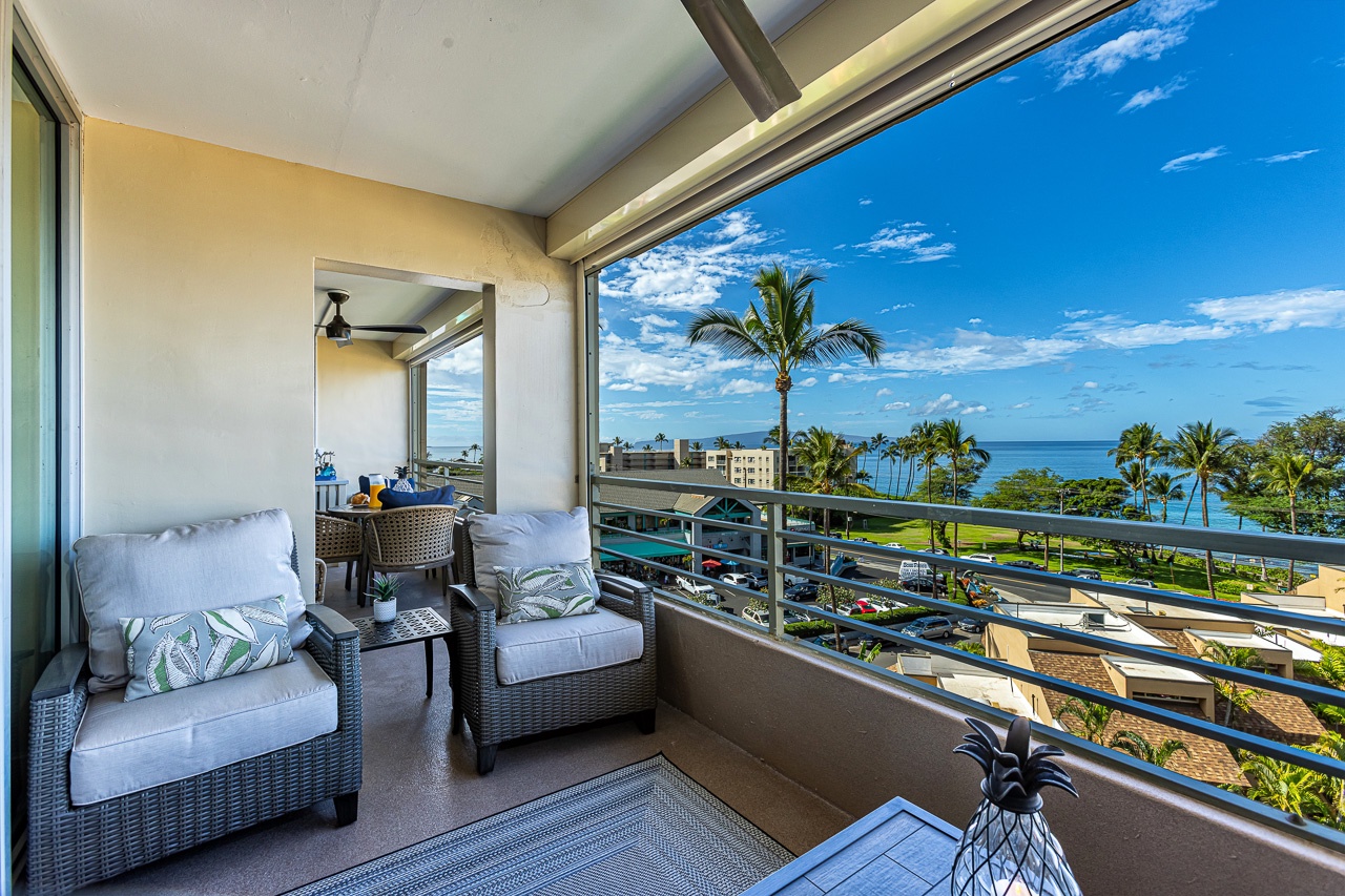 Kihei Vacation Rentals, Kamaole Beach Royal 610 - Wicker chairs on the lanai look past the rooftops straight to the water.