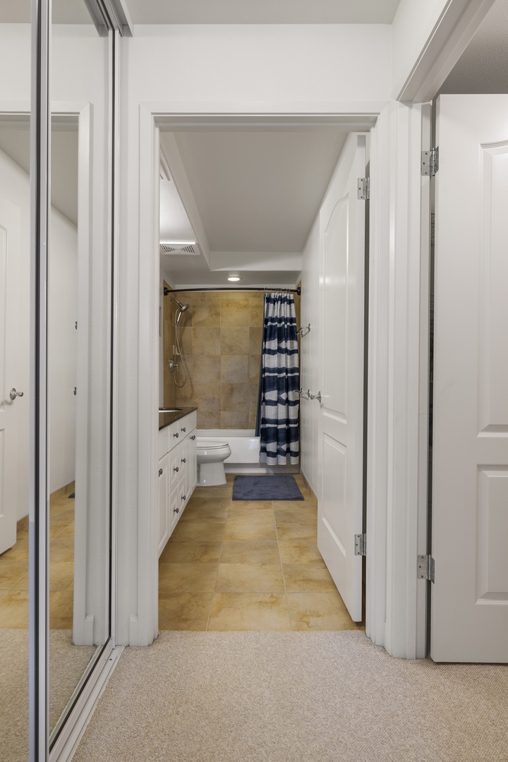The nearby full bathroom features a spacious vanity and tub-shower combination, providing convenience and comfort during your stay.