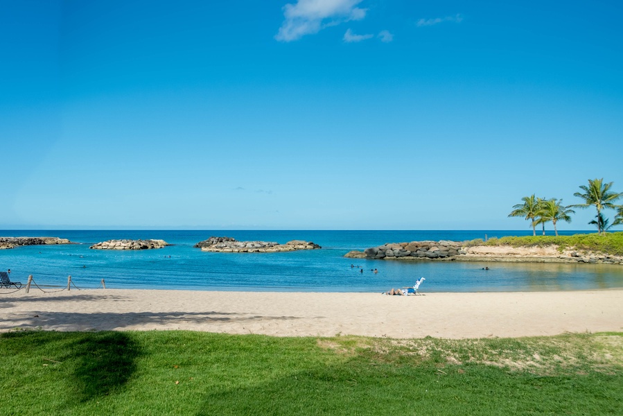Kapolei Vacation Rentals, Fairways at Ko Olina 7A - Pristine beach with crystal-clear waters, rocky outcrops, and swaying palm trees creates a perfect tropical setting.