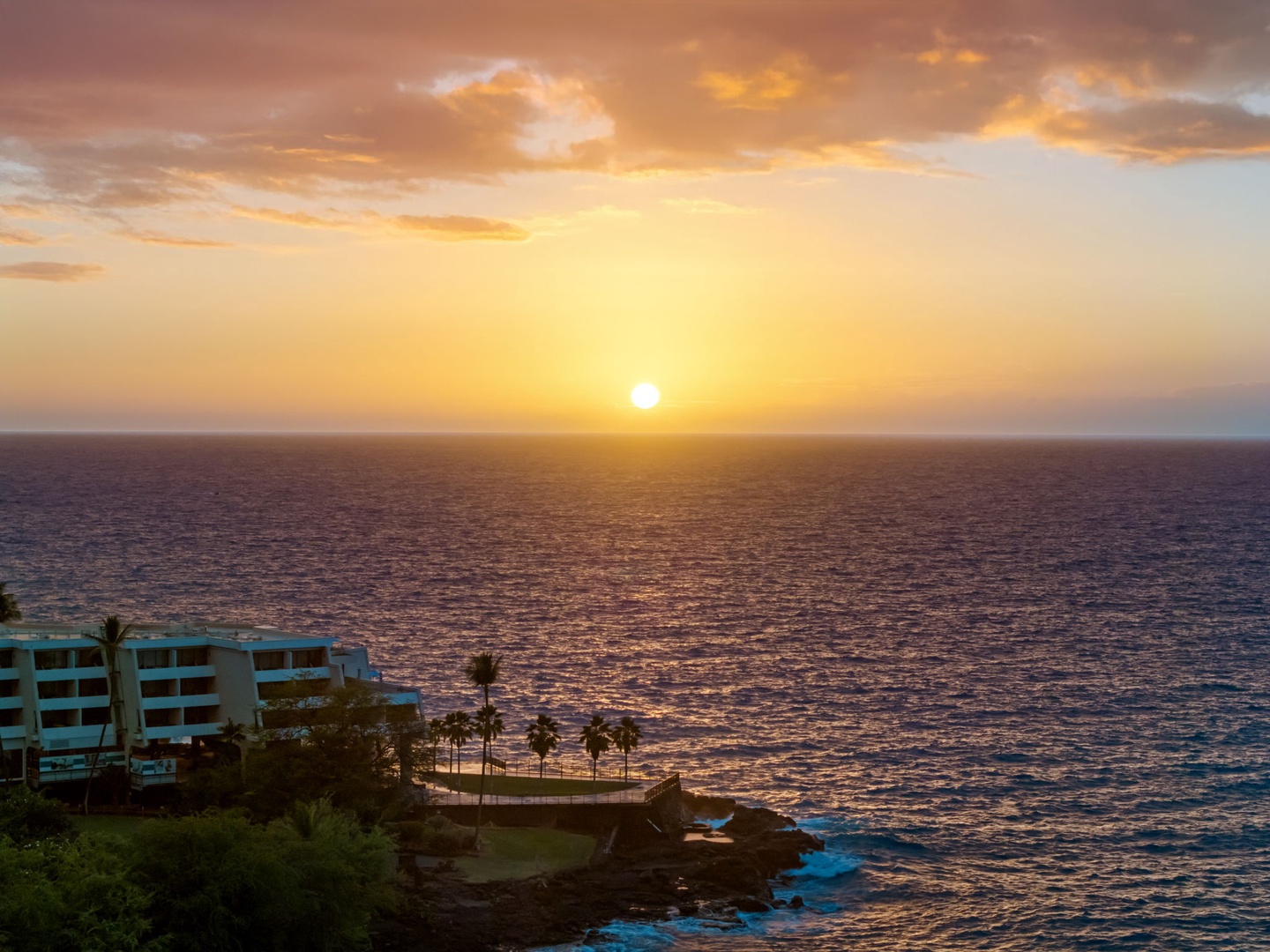 Kailua-Kona Vacation Rentals, Hahalua Bay Villa - Golden sunset paints the sky above oceanfront property with dramatic clouds and shimmering waters stretching to the horizon.