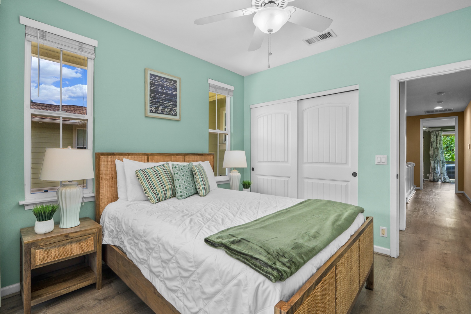 Princeville Vacation Rentals, Kaimana Villa - Relax in your tranquil bedroom featuring soothing mint walls, crisp white linens, and warm wicker furnishings that create a coastal retreat atmosphere.