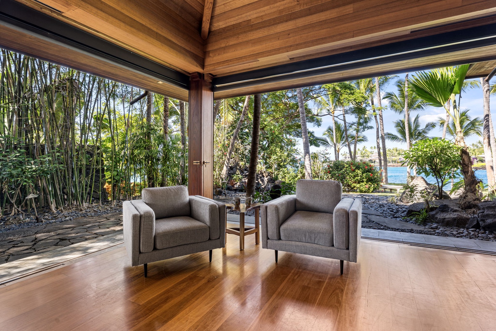 Kailua-Kona Vacation Rentals, Hahalua Bay Villa - Your primary bedroom opens to lush tropical gardens and sparkling ocean views, where warm wood floors meet panoramic windows.