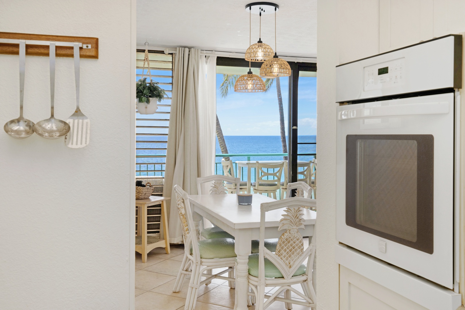Kihei Vacation Rentals, Punahoa Beach 205 - Pineapple-carved chairs pull up to a table with the ocean waiting just past the slider.