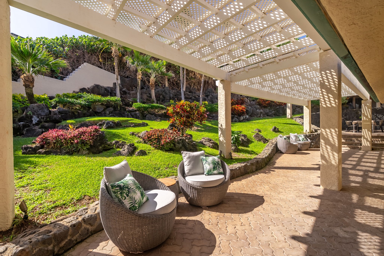 Honolulu Vacation Rentals, Black Point Ocean Villa - Relax in your private lanai chairs while gazing at the lush tropical garden with vibrant plants and palm trees.