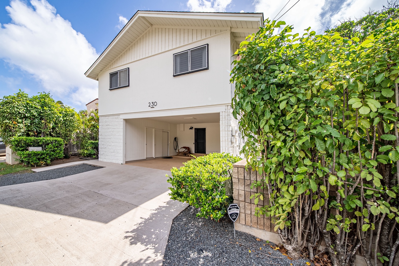 Honolulu Vacation Rentals, Honolulu Beachfront Retreat - Charming front view of the home featuring a spacious driveway and tropical landscaping, offering a warm island welcome.