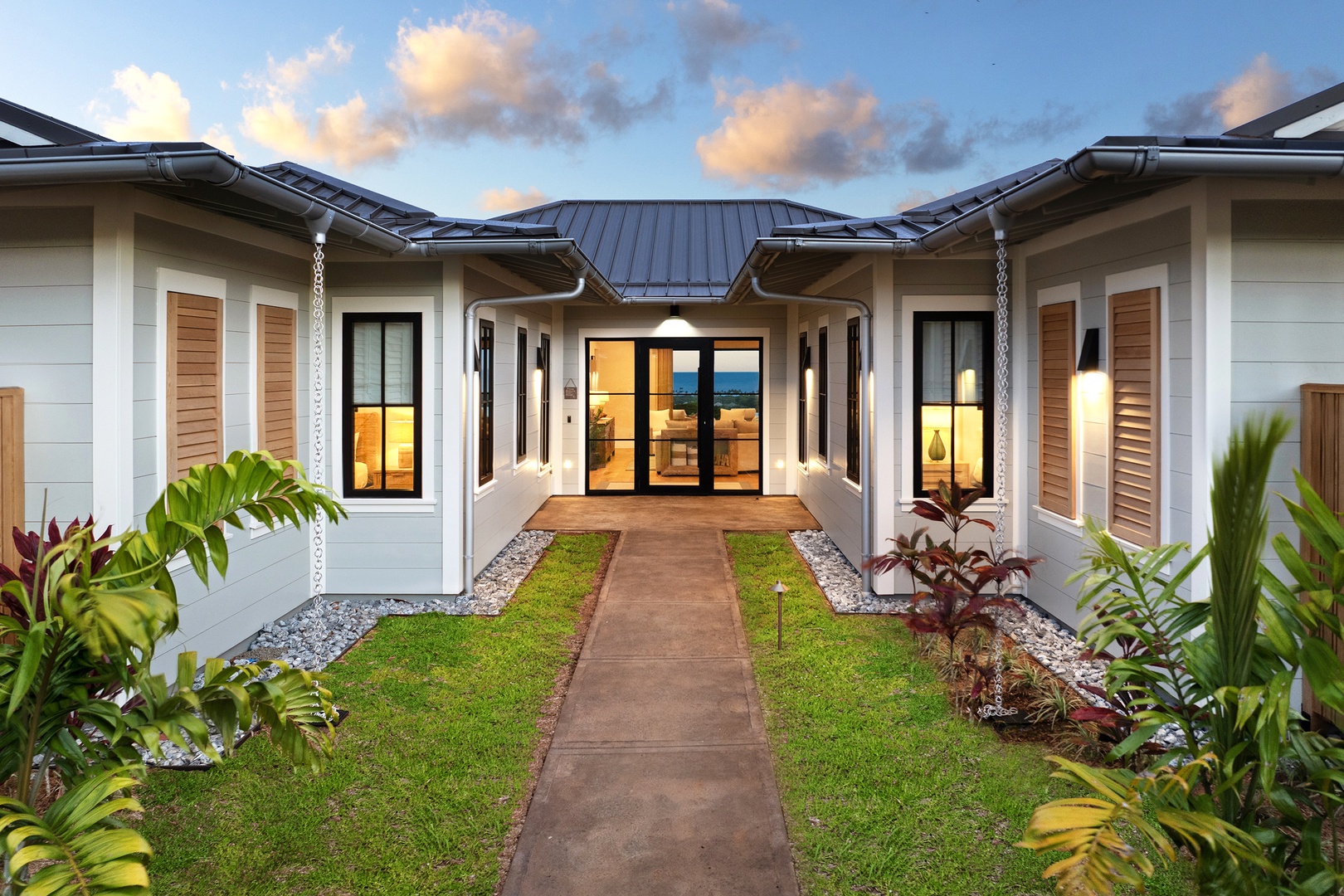 Koloa Vacation Rentals, Hali'a Mai - Evening settles over the courtyard entry, the walkway lit and the lawn glowing green.