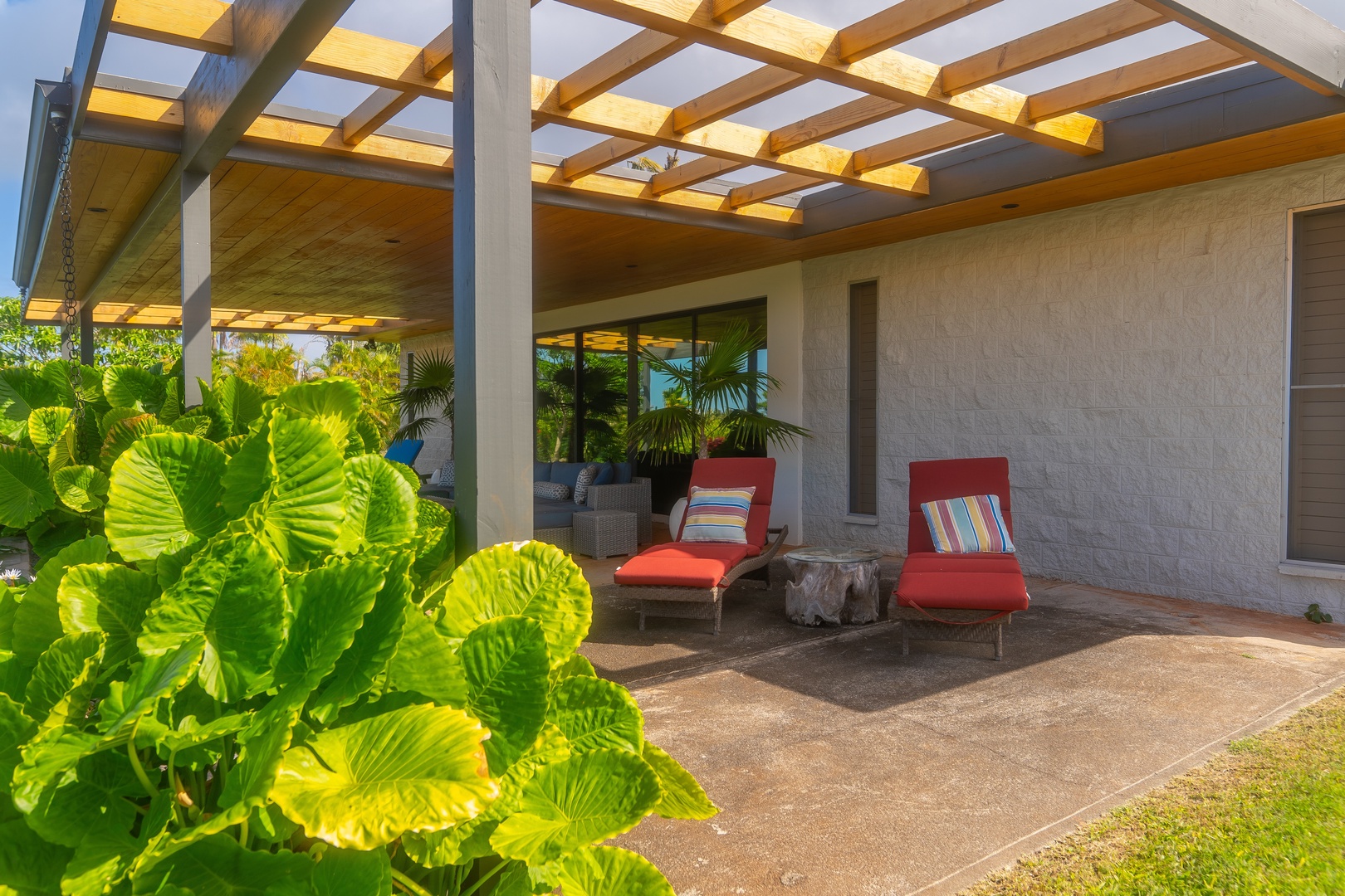 Haleiwa Vacation Rentals, Hale Mahina - Unwind under the shaded pergola with cushioned loungers and lush greenery all around.