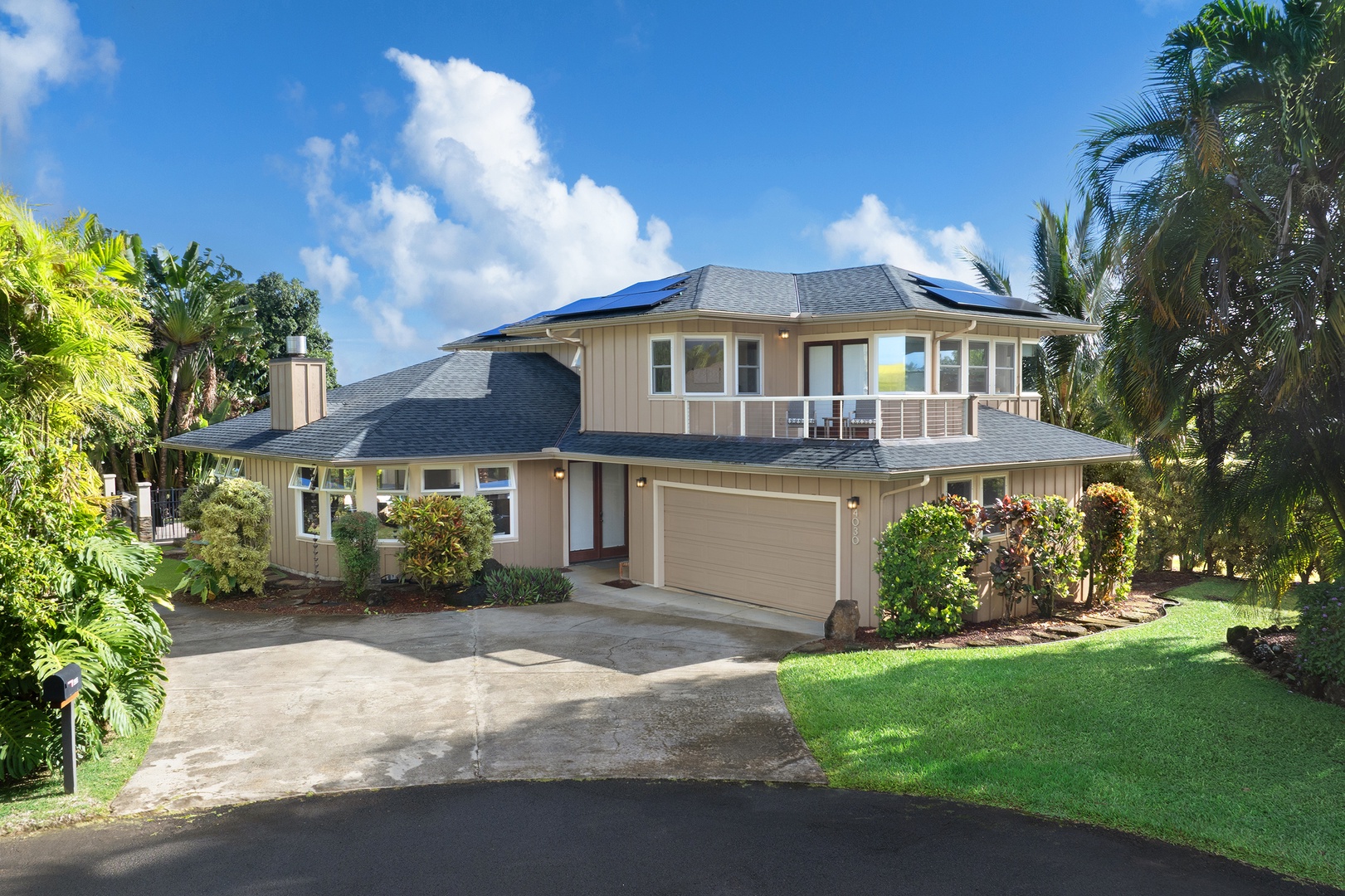 Princeville Vacation Rentals, Pohaku Villa - Modern two-story tropical home with solar panels, landscaped gardens, and palm trees in a peaceful residential setting.