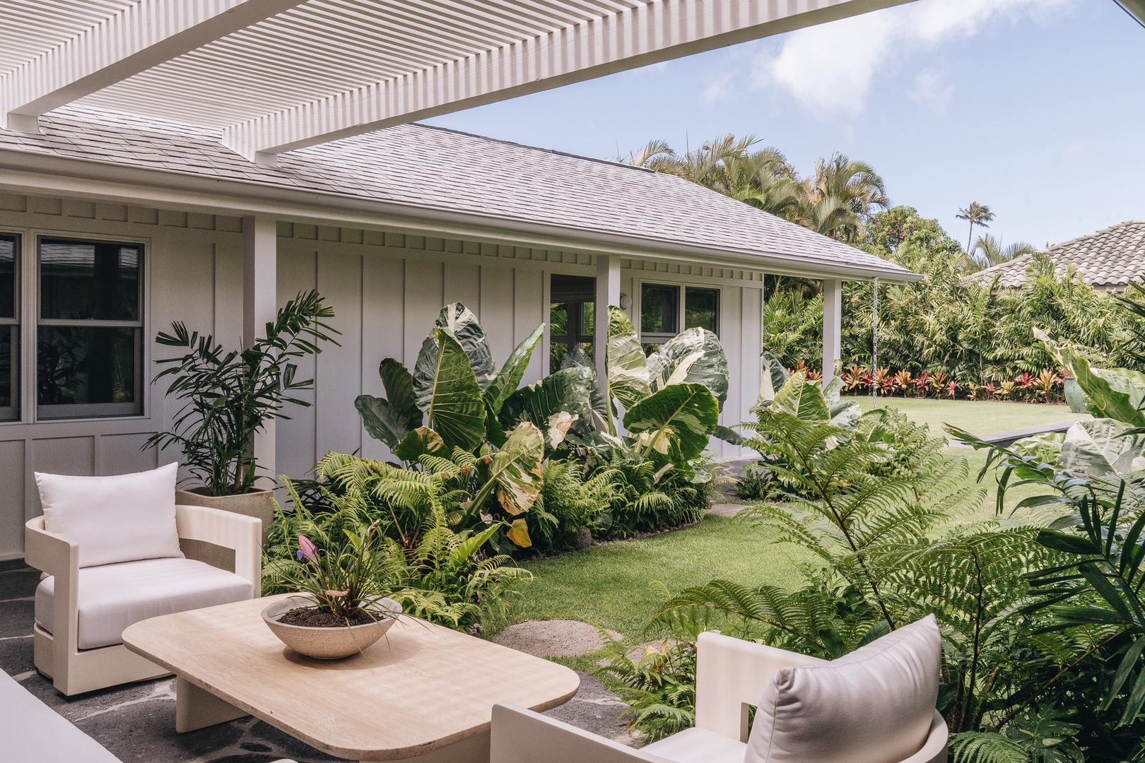 Honolulu Vacation Rentals, Surfside Bungalow** - A peaceful outdoor seating area surrounded by lush tropical landscaping.