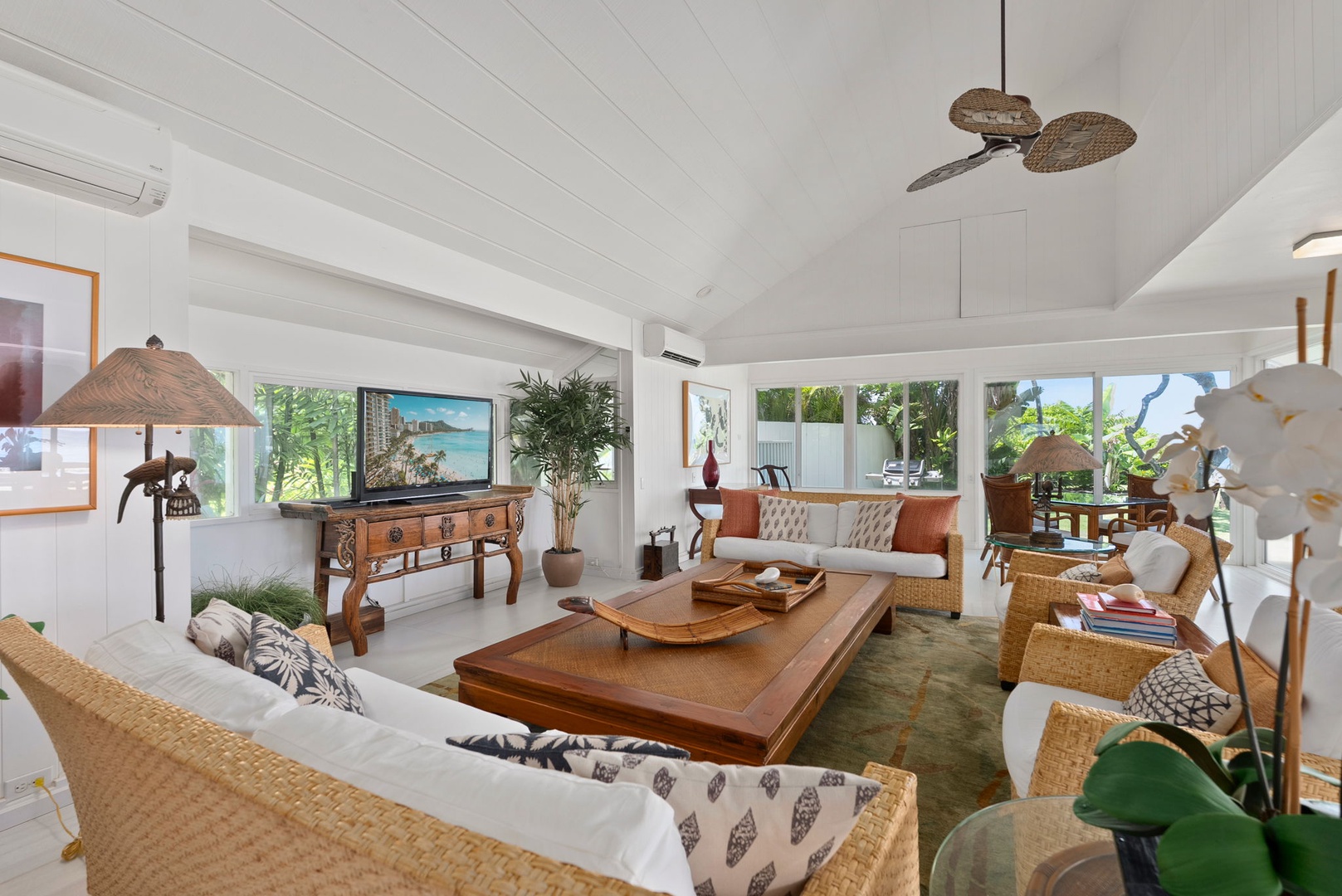 Waianae Vacation Rentals, Ma'ili Blue Estate - Relax in your tropical-inspired living room with wicker furnishings, warm wood accents, and peaceful garden views through wraparound windows.