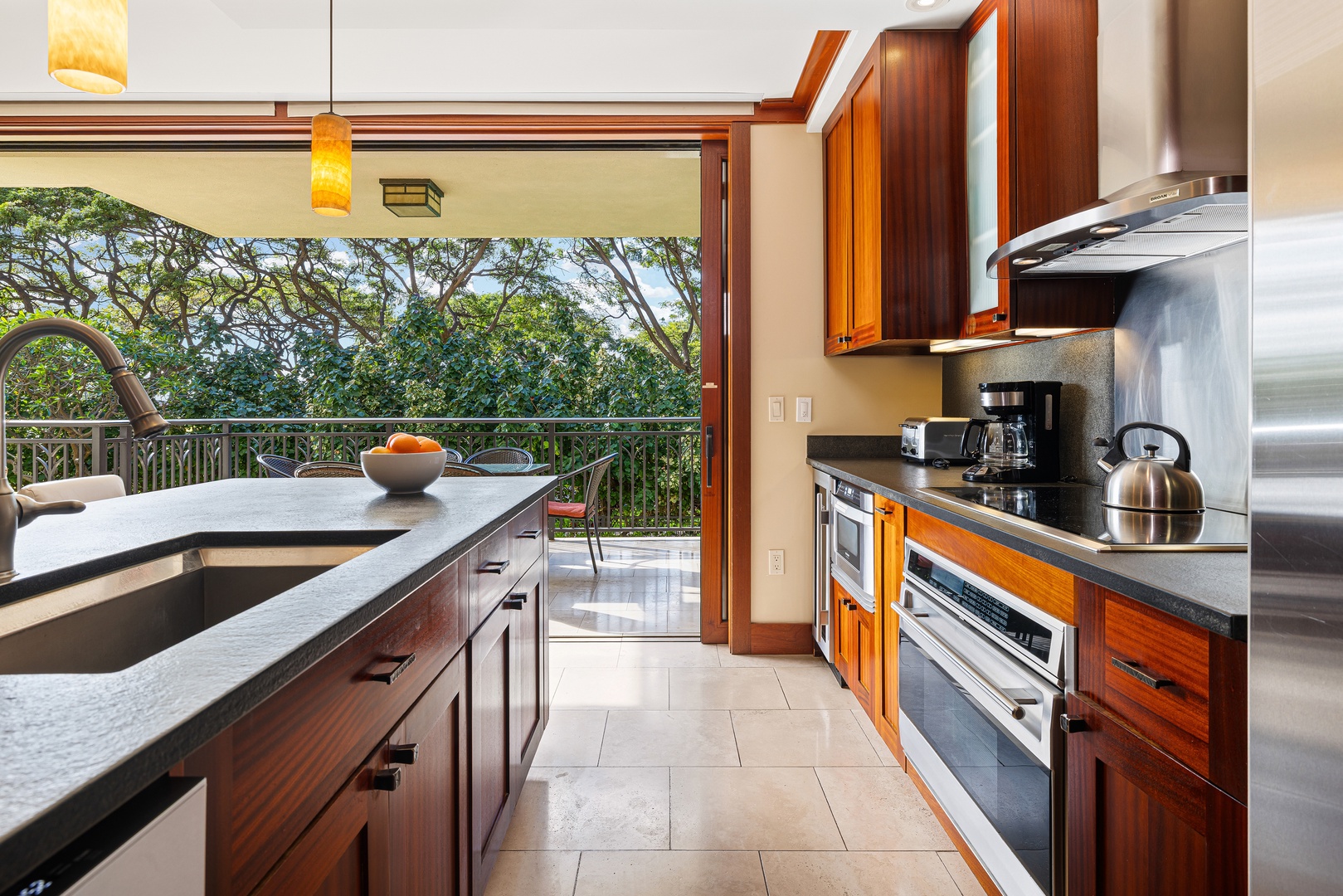 Your elegant kitchen opens onto a private balcony with lush treetop views, blending modern appliances and rich wood cabinetry for a seamless indoor-outdoor cooking experience.