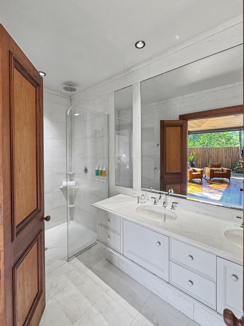 Kailua-Kona Vacation Rentals, Hahalua Bay Villa - Your spa-like bathroom features marble finishes, a glass-enclosed shower, and views of the private outdoor seating area through elegant wood-framed windows.