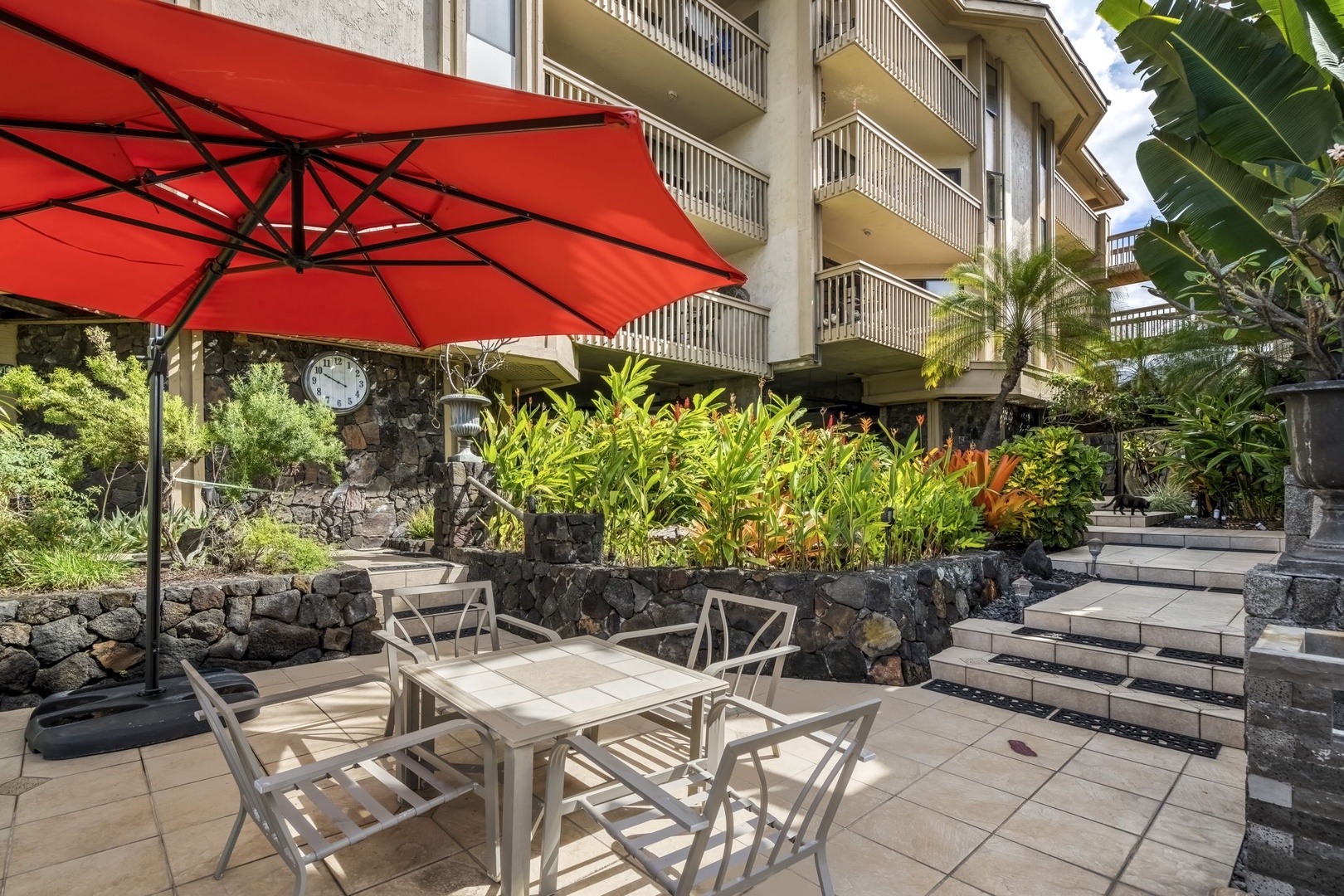 Kailua Kona Vacation Rentals, Royal Kahili 401A - Outdoor dining area with seating for six, shaded by vibrant red umbrellas.