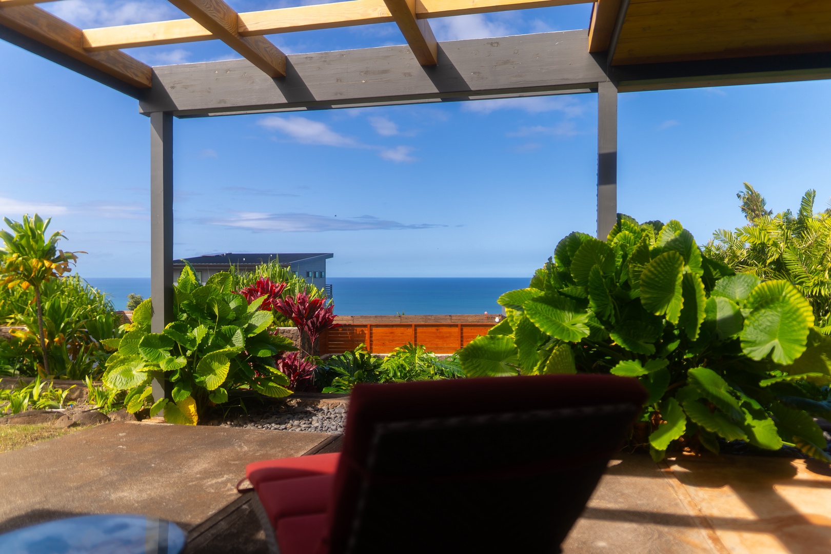 Haleiwa Vacation Rentals, Hale Mahina - Take in sweeping ocean views from a cozy lanai seating area framed by vibrant island foliage.