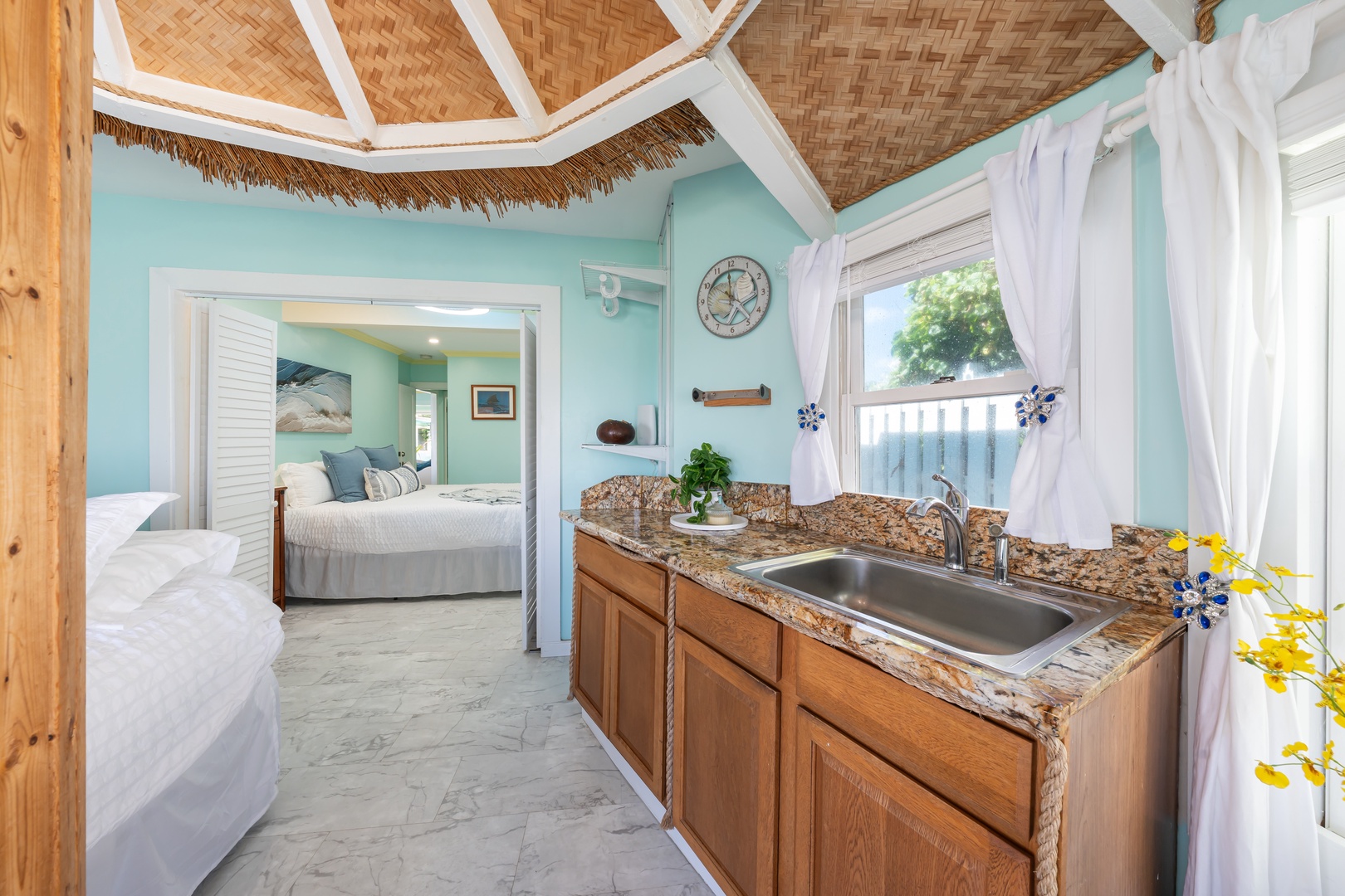 Hauula Vacation Rentals, Private Beach Paradise - Full kitchenette in the same airy room, wood cabinets under the woven ceiling.