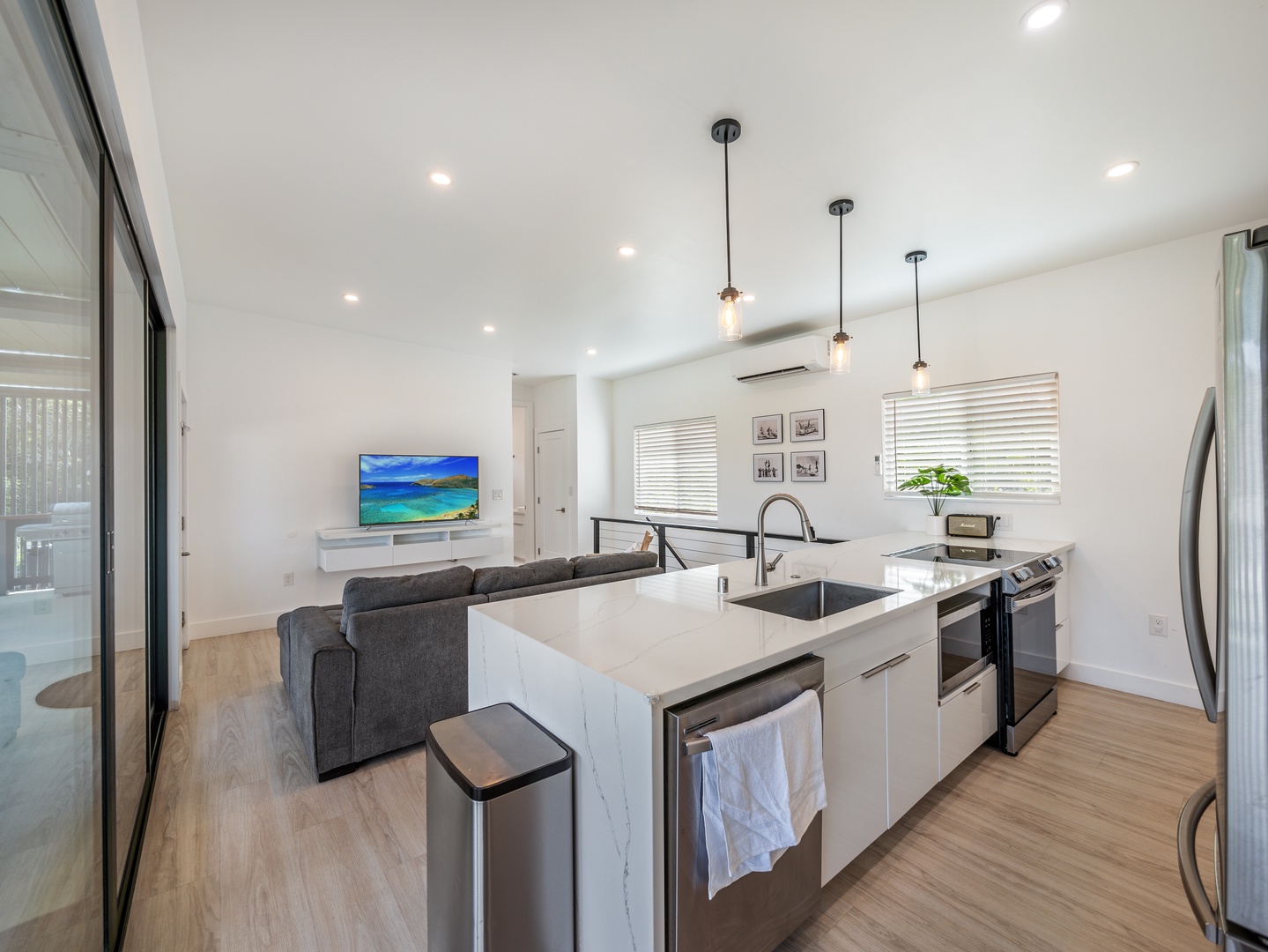 Haleiwa Vacation Rentals, Sunset Beach Island Retreat - The kitchen features modern appliances, a sleek island with bar seating, and pendant lighting