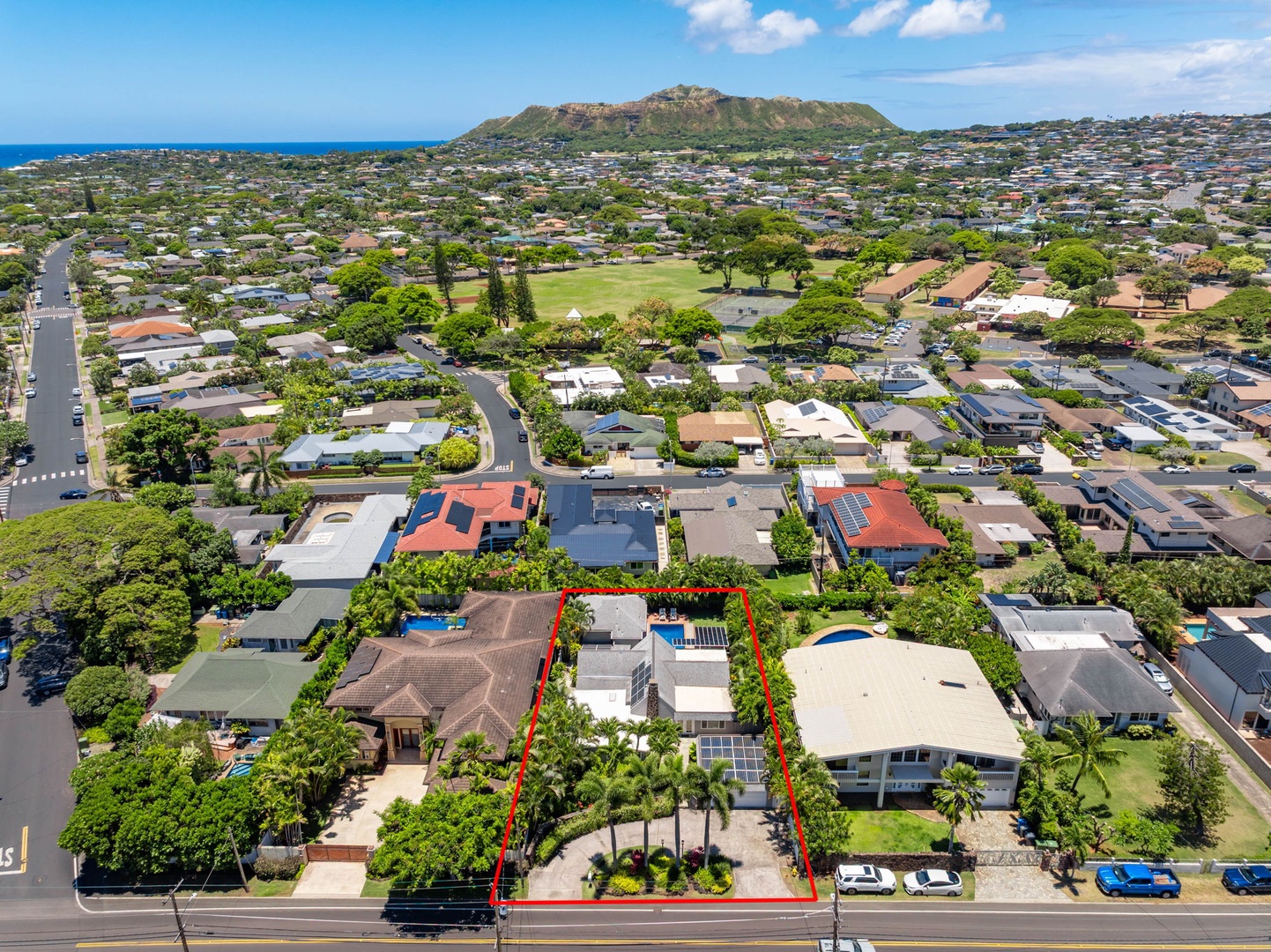 Honolulu Vacation Rentals, Ho'okipa Villa - Aerial view of a residential property located in a coastal neighborhood, with volcanic mountain backdrop, green spaces, and ocean views visible in the surrounding area.