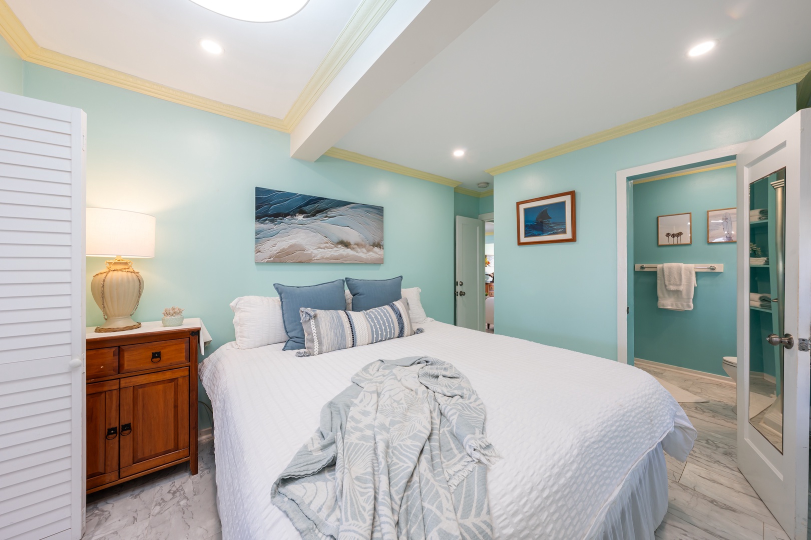 Hauula Vacation Rentals, Private Beach Paradise - Coastal-inspired bedroom with a plush bed, soft lighting, and a private ensuite bath.