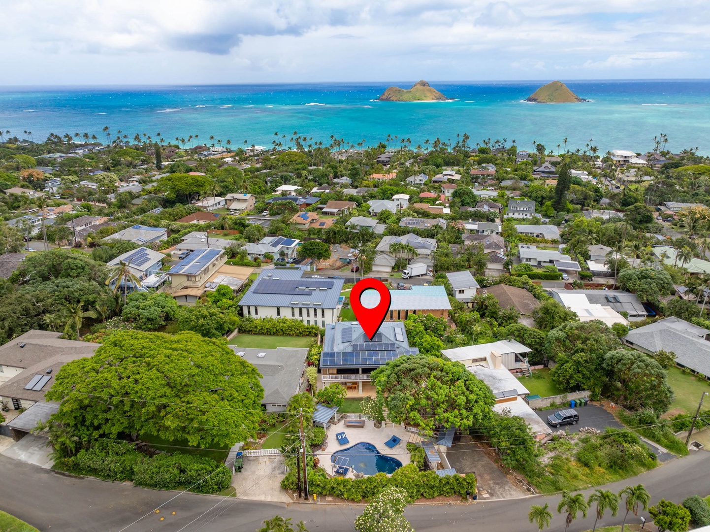 Kailua Vacation Rentals, Leaf House - Aerial view of a beachside property nestled in a tropical residential neighborhood with ocean views, palm trees, and nearby islands on the horizon.