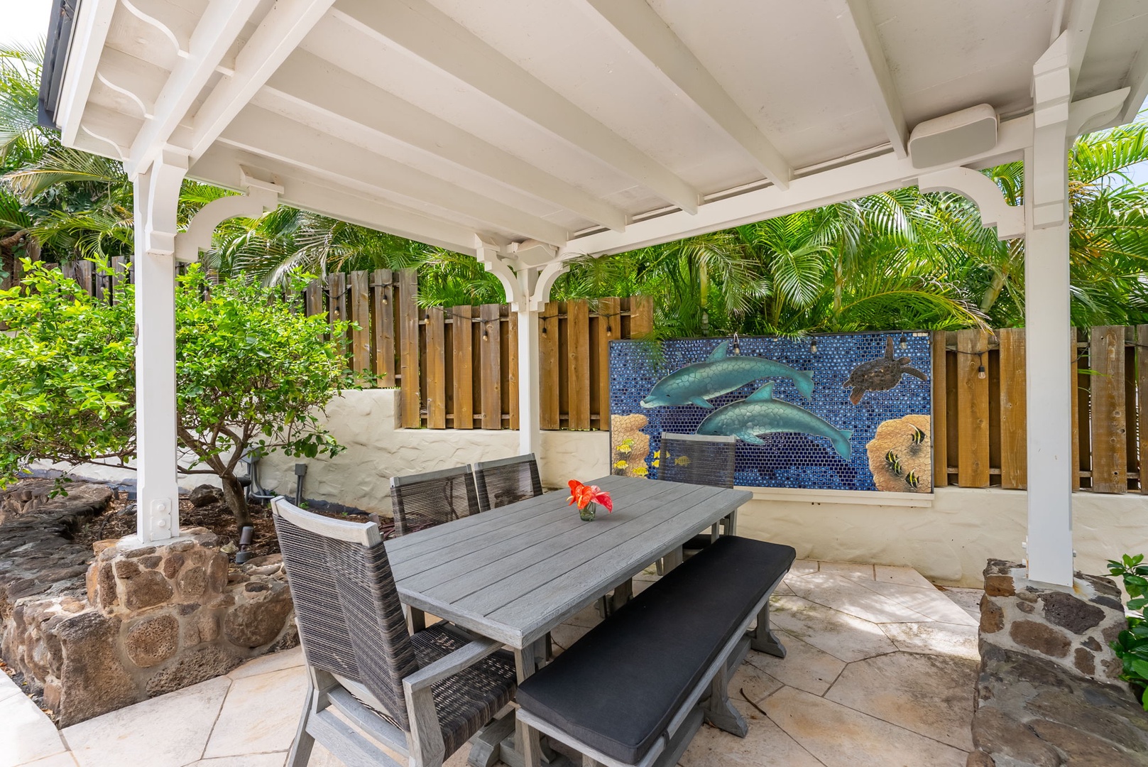 Kailua Vacation Rentals, Leaf House - Your private patio offers alfresco dining under a charming pergola, surrounded by lush tropical palms and artful dolphin mosaic—a peaceful retreat for morning coffee or evening gatherings.