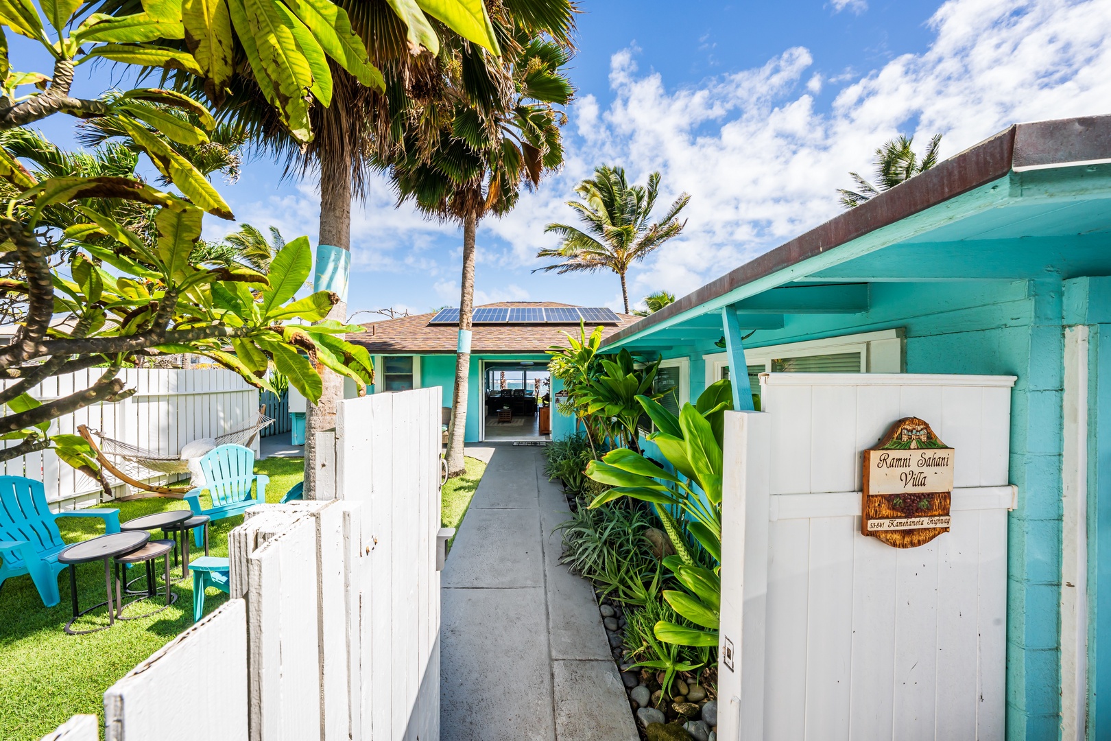 Hauula Vacation Rentals, Private Beach Paradise - Inviting beach cottage entrance framed by palms and lush coastal greenery.