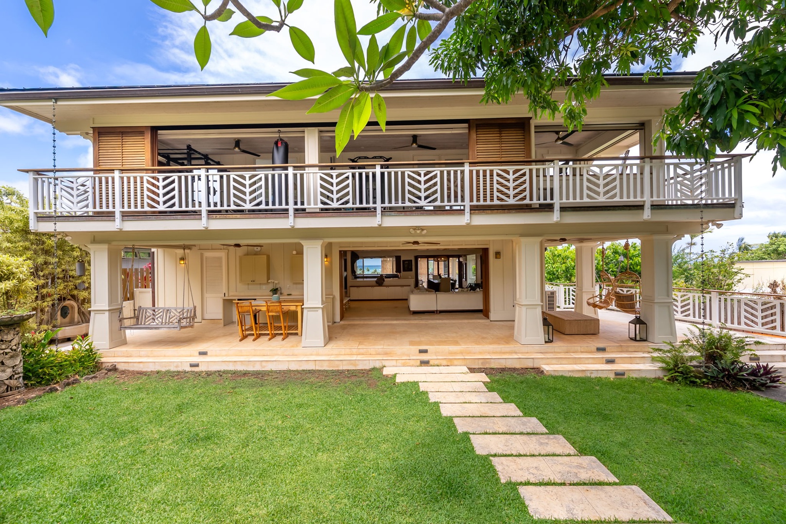 Kailua Vacation Rentals, Leaf House - Spacious two-story Hawaiian-style home features open-air living spaces, decorative balcony railings, and lush tropical landscaping with a stepping stone walkway through manicured lawn.