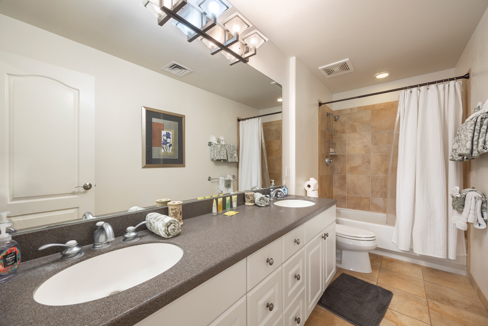 Your spacious bathroom features dual sinks, elegant lighting, and a refreshing shower-tub combo for ultimate comfort.