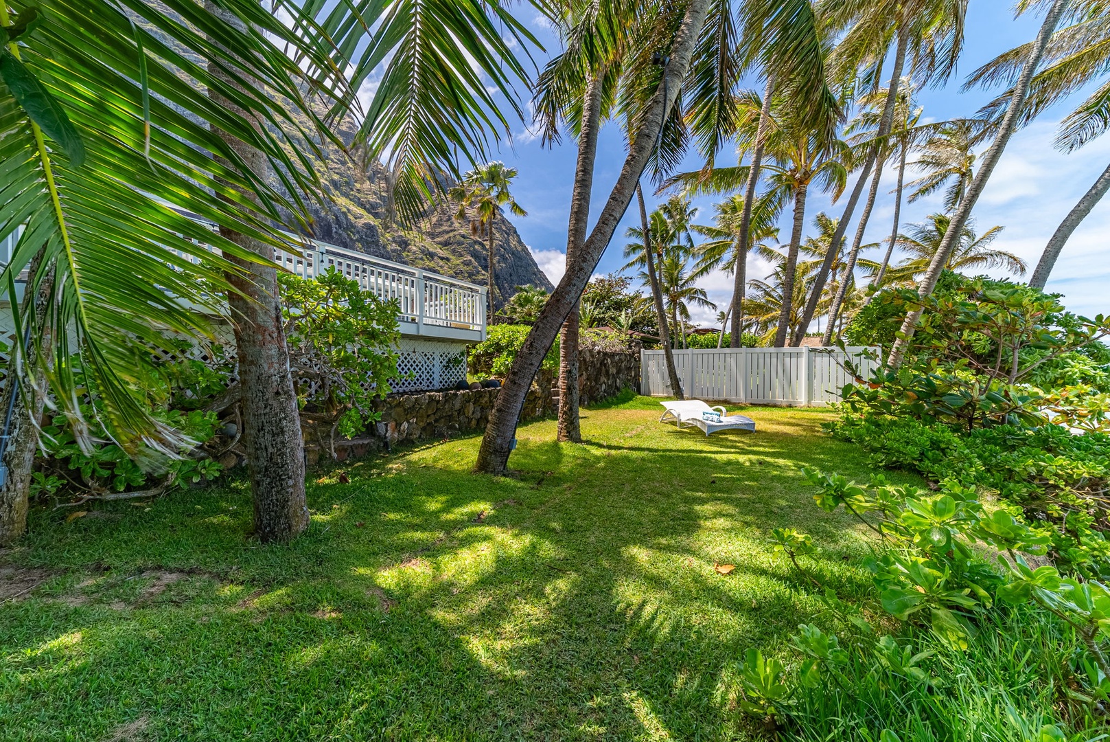 Waimanalo Vacation Rentals, Mana Kai at Waimanalo - Relax on the chaise lounge amidst a lush grassy expanse, with the luxurious home and majestic mountains framing the perfect backdrop.