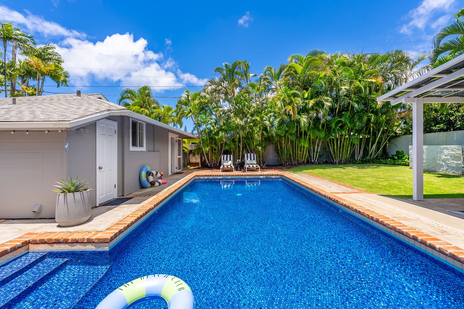 Honolulu Vacation Rentals, Ho'okipa Villa - Private pool surrounded by lush tropical palms and sunny lounge chairs, perfect for relaxing under blue skies in your own backyard paradise.