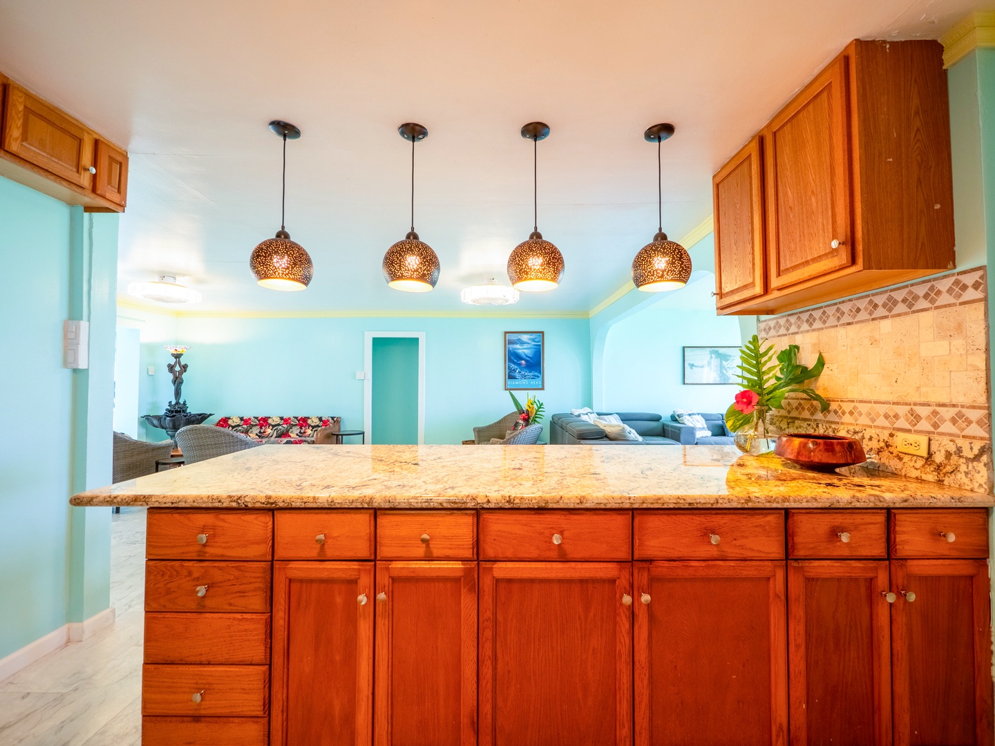 Hauula Vacation Rentals, Private Beach Paradise - Step into your tropical kitchen paradise with warm wood cabinets, granite counters, and coastal pendant lighting creating the perfect space for your vacation meals.