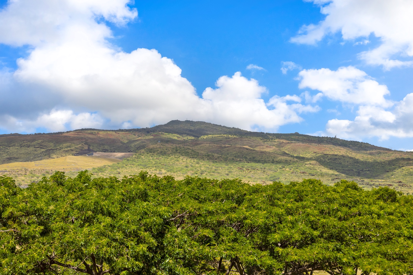 Kapolei Vacation Rentals, Ko Olina Beach Villas B506 - Dramatic mountain landscape with rolling hills and lush green vegetation under a brilliant blue sky with white clouds.
