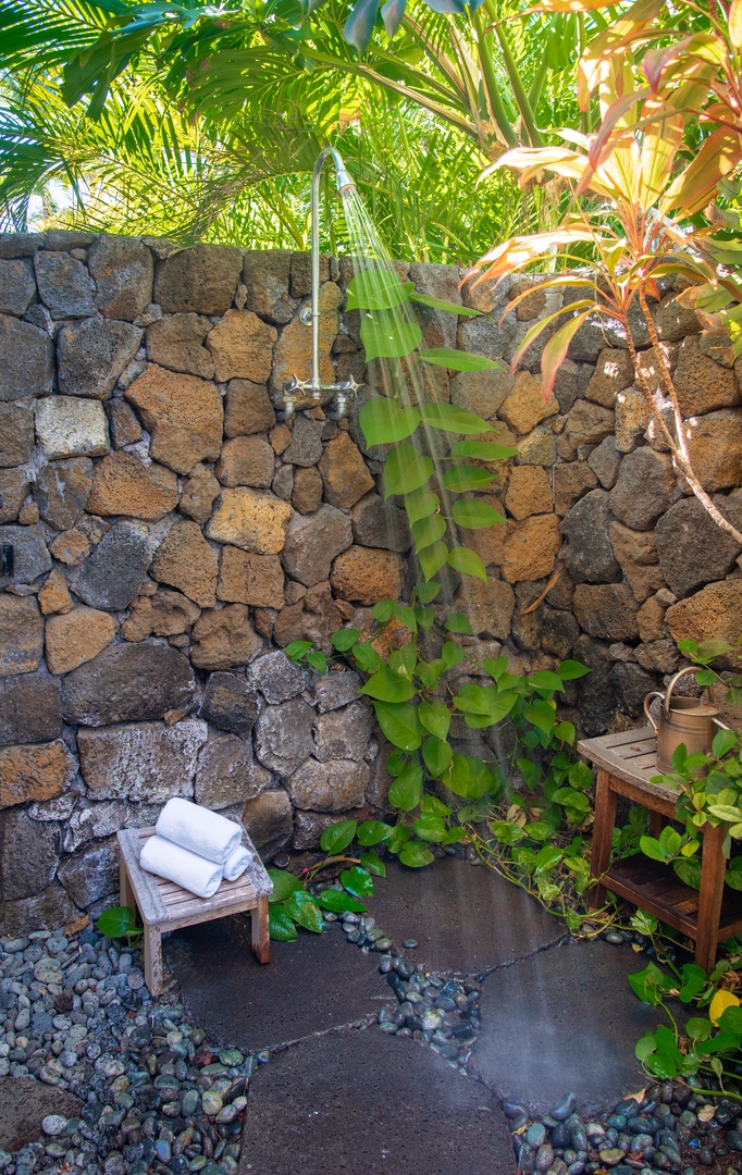 Kamuela Vacation Rentals, Champion Ridge Elegance - Guest Suite 2 outdoor shower surrounded by natural stone and tropical foliage.