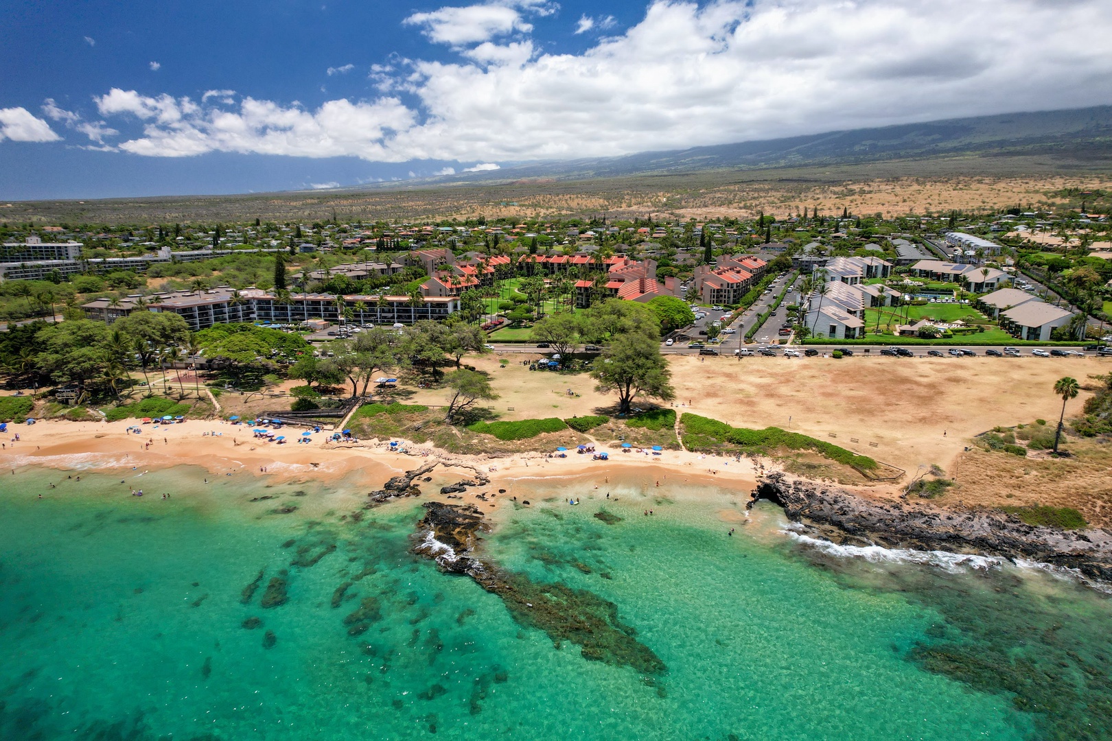 Kihei Vacation Rentals, Kamaole Sands 5310 - The beach sits just across the road, turquoise water and a rocky point breaking the shoreline into coves.