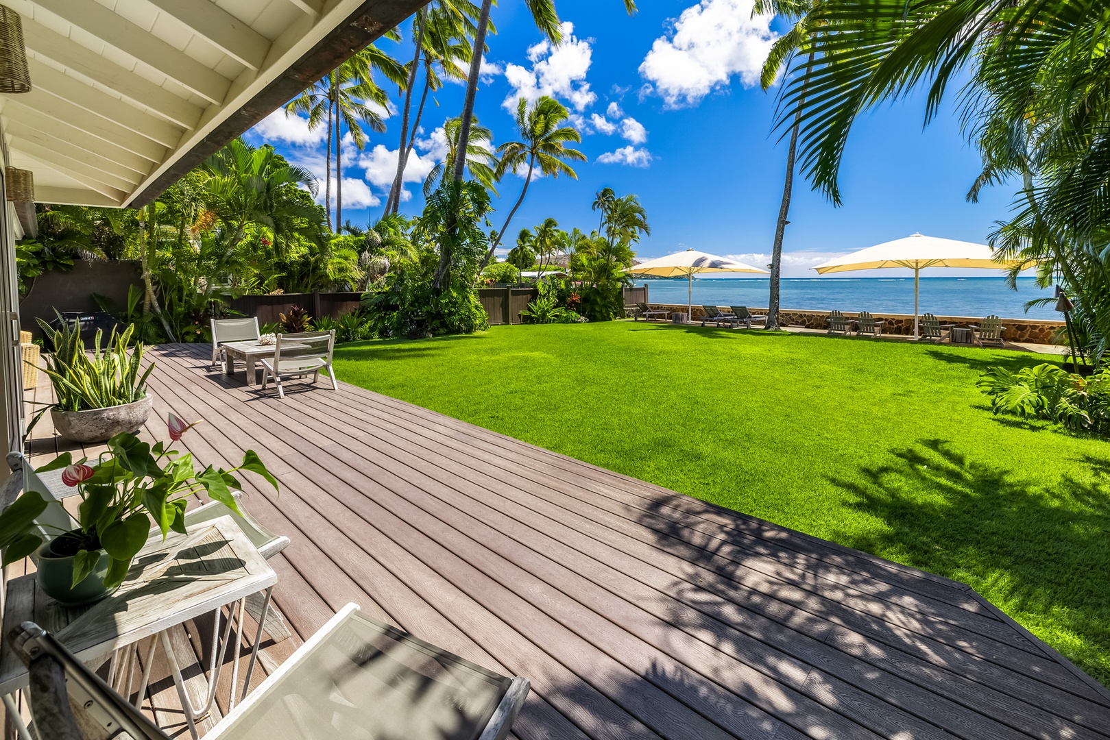 Honolulu Vacation Rentals, Moana Lani - Main House - Walk off the deck and straight across the grass toward the umbrellas and the ocean.