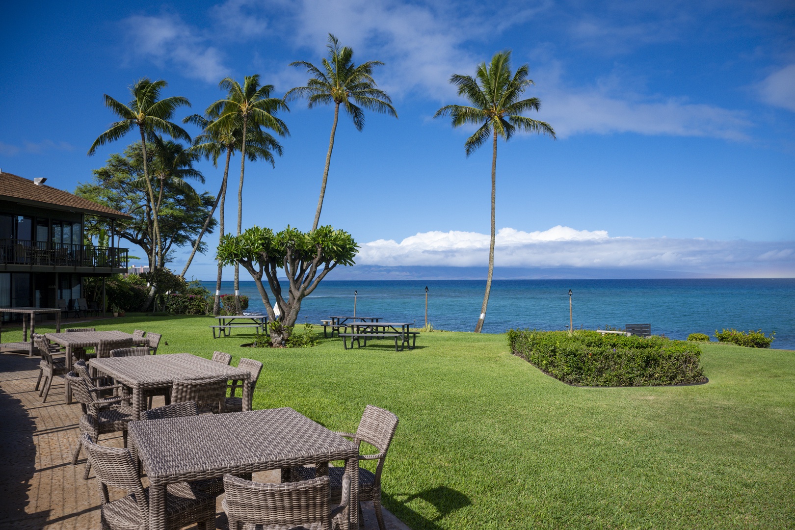 Lahaina Vacation Rentals, Polynesian Shores 114 - Dinner under the palms with the ocean filling the space past the table.