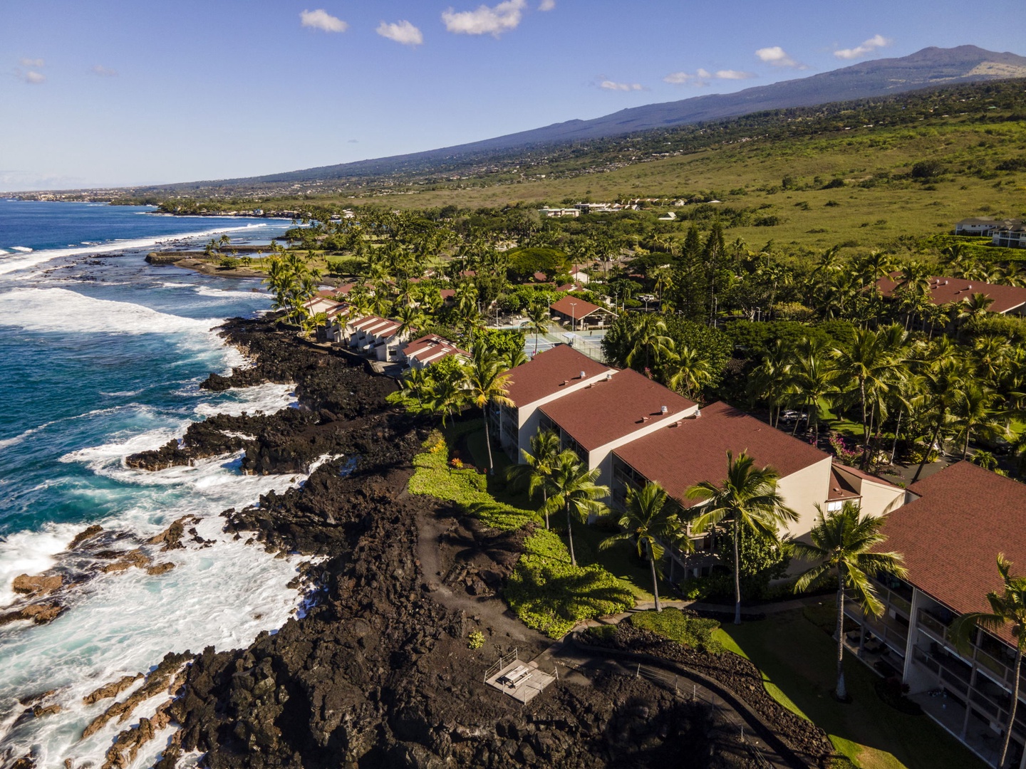 Kailua Kona Vacation Rentals, Keauhou Kona Surf & Racquet 1104 - A drone's view of the red-roofed grounds strung along the black lava coast.
