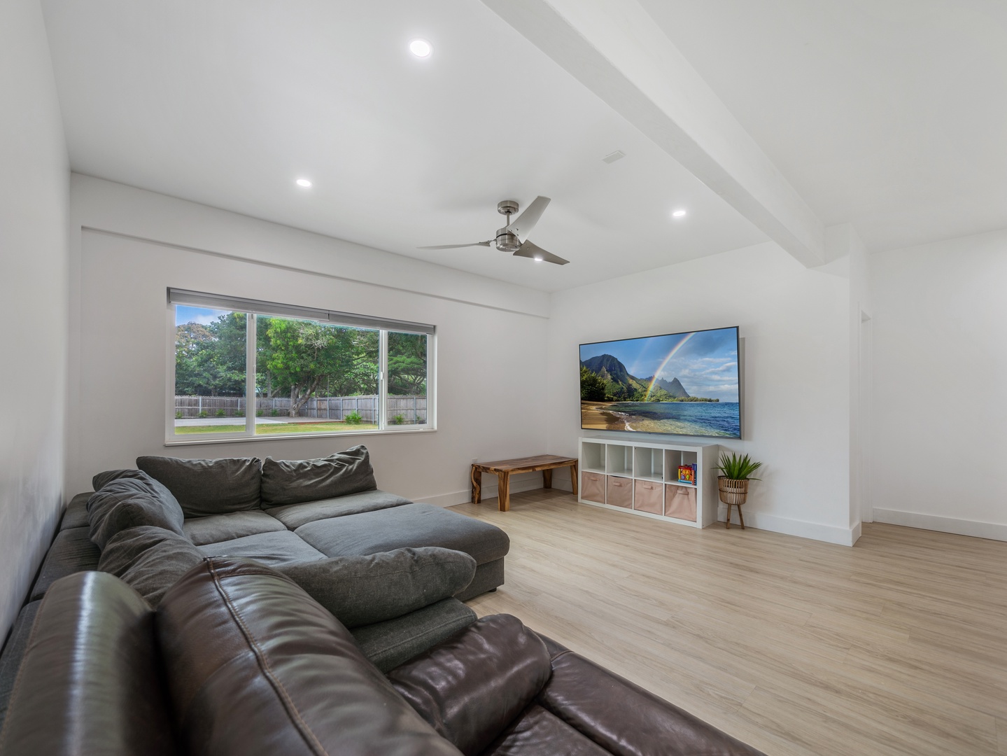 Haleiwa Vacation Rentals, Sunset Beach Island Retreat - The bright and airy third bedroom offers a comfortable sectional sofa and a large flat-screen TV, perfect for cozy movie nights or enjoying some downtime.