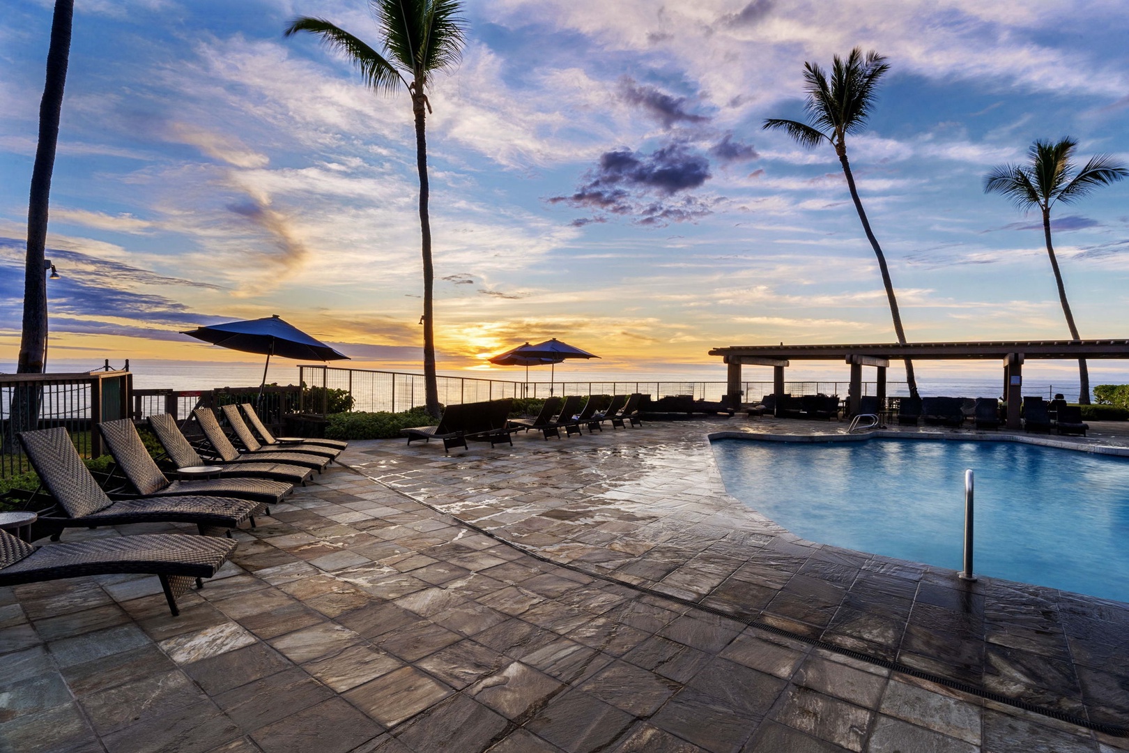Kailua Kona Vacation Rentals, Kanaloa at Kona 1606 - The pool deck at golden hour, palms silhouetted against a painted sky.