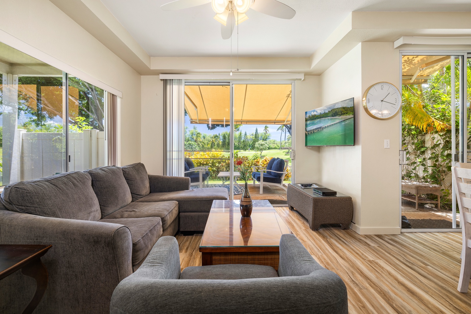 Sink into plush gray sofas while tropical breezes flow through your bright living space, where garden views create your perfect retreat.