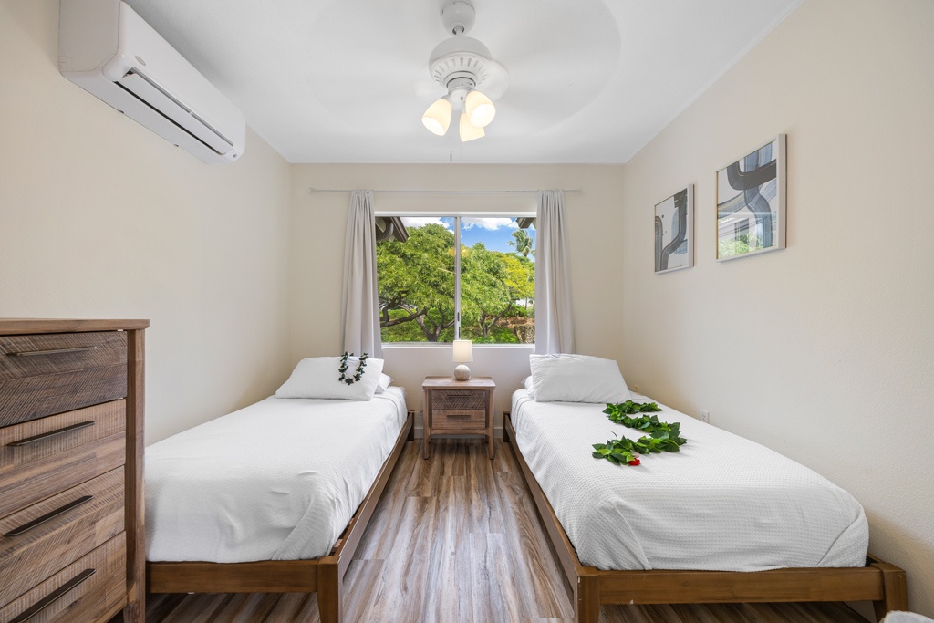 Third bedroom with two twin beds and a garden view, perfect for kids, friends, or flexible sleeping arrangements.