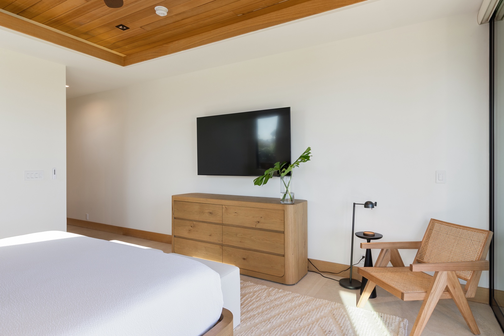 Kamuela Vacation Rentals, 5BD Mauna Lani Lux Ocean Estate (OE12) at One Ocean - Unwind in your serene bedroom featuring warm wood tones, a wall-mounted TV, and stylish furniture for the perfect retreat.