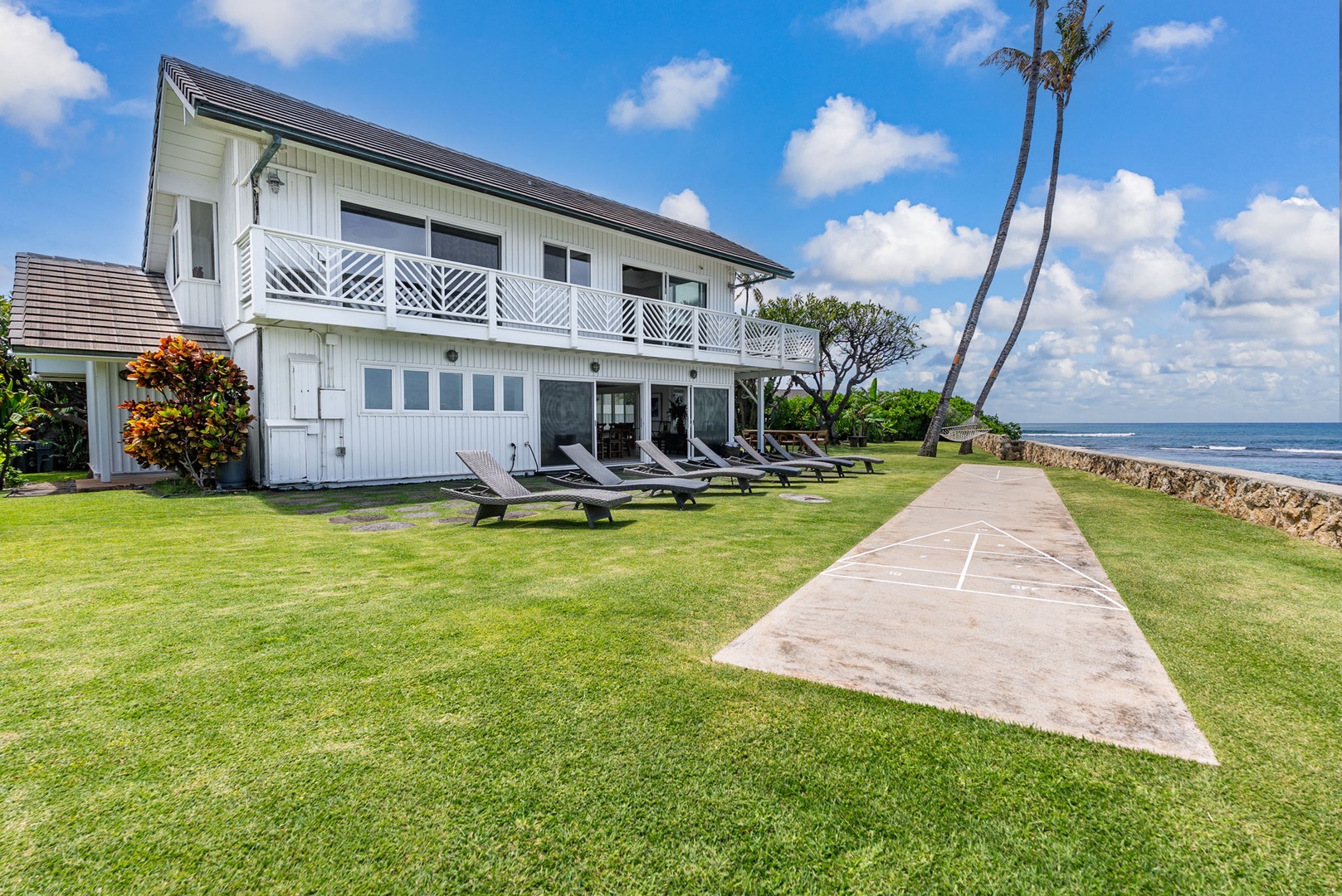 Waianae Vacation Rentals, Ma'ili Blue - Home with oceanfront lawn, direct beach access, lounge chairs, and tropical palm trees under bright blue skies.
