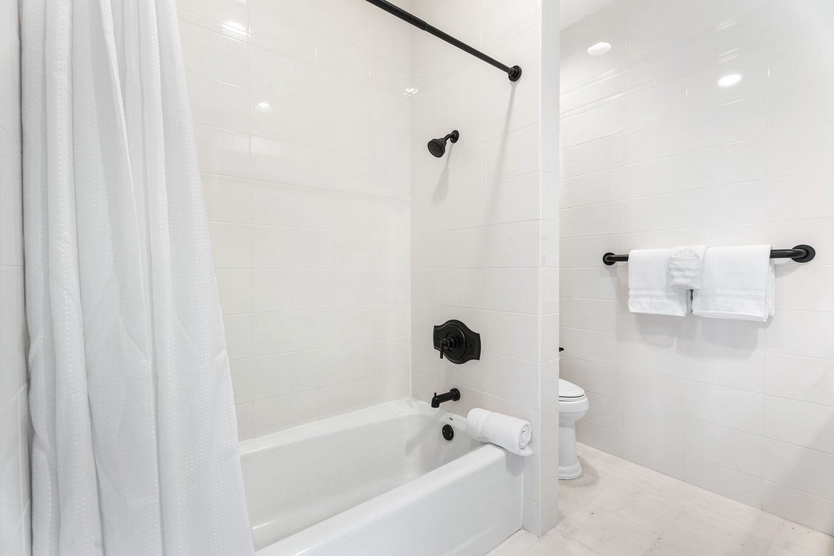 Kailua Kona Vacation Rentals, Hale Nai'a - Step into your spotless bathroom featuring a relaxing tub-shower combo with crisp white tiles and fresh towels waiting for you.