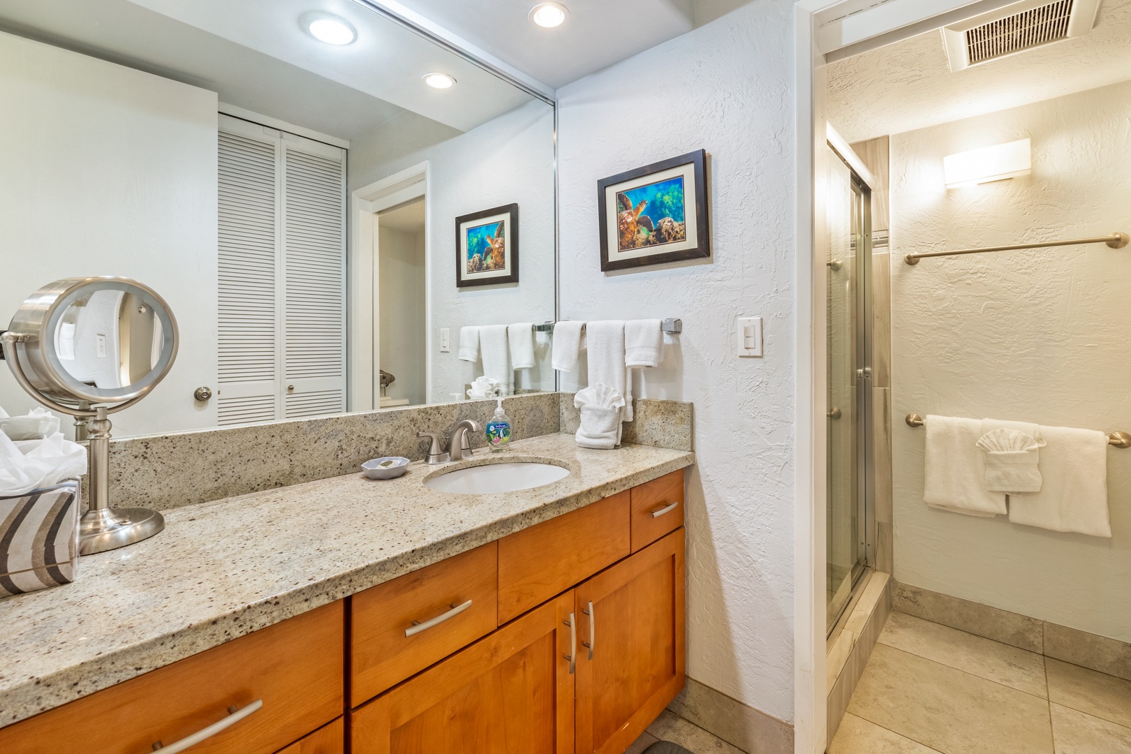 Lahaina Vacation Rentals, Papakea K-105 - The bathroom features a granite countertop vanity and a walk-in shower, offering a blend of style and convenience for a relaxing stay.