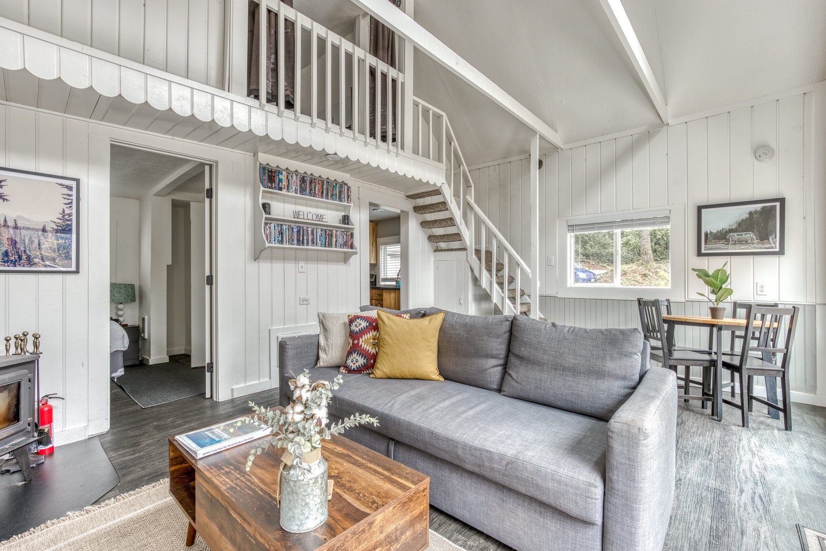 Rhododendron Vacation Rentals, Riverbend Cabin #2 - Step into the open-concept living area of the cabin, furnished with a comfortable couch, coffee table, 55" flatscreen Smart television, a wood burning fireplace, hundreds of DVDs