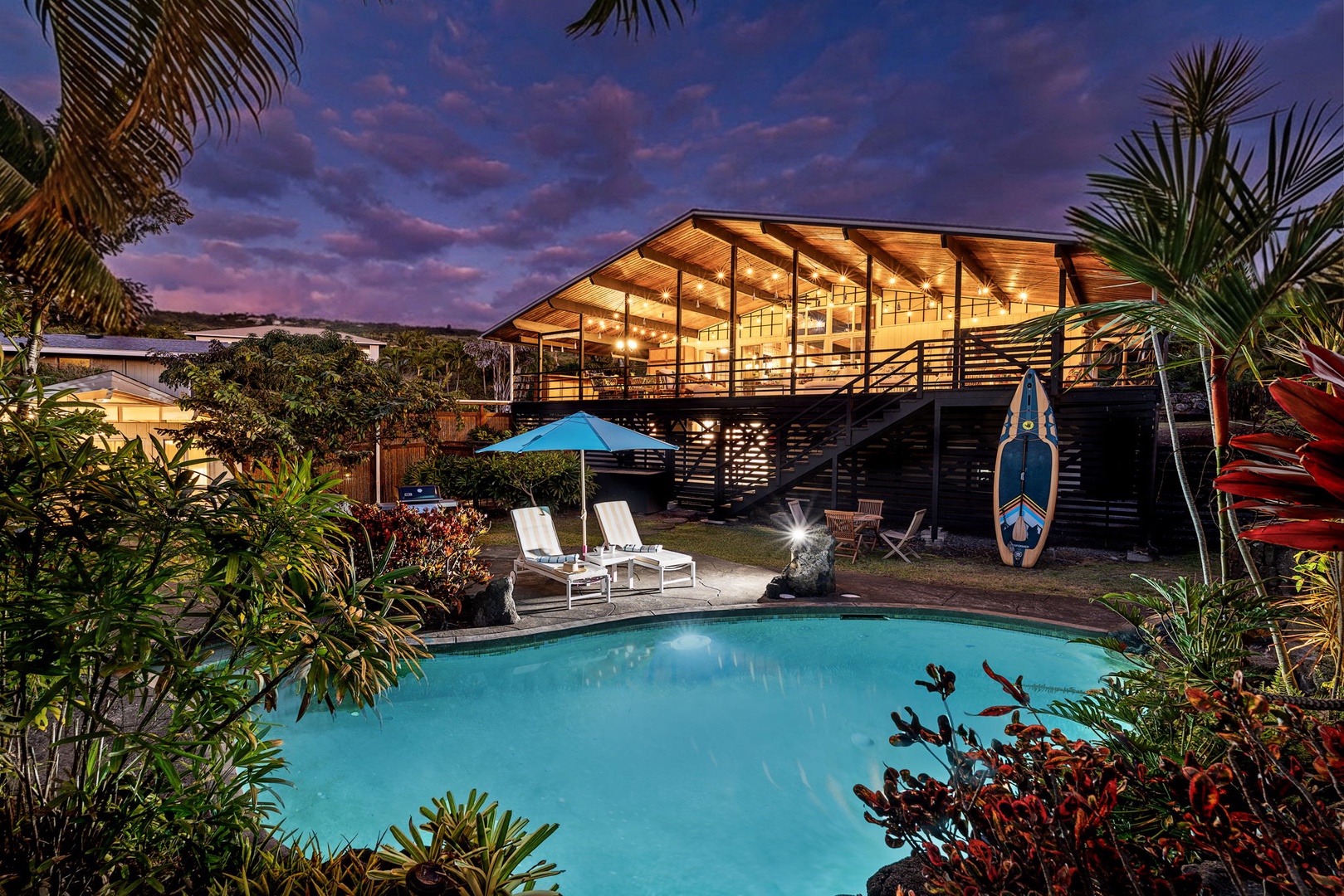 Kailua Kona Vacation Rentals, Mai Tai Manor - Modern tropical retreat with stunning architecture illuminated against a dramatic purple sky, featuring a pristine pool and lush garden setting.