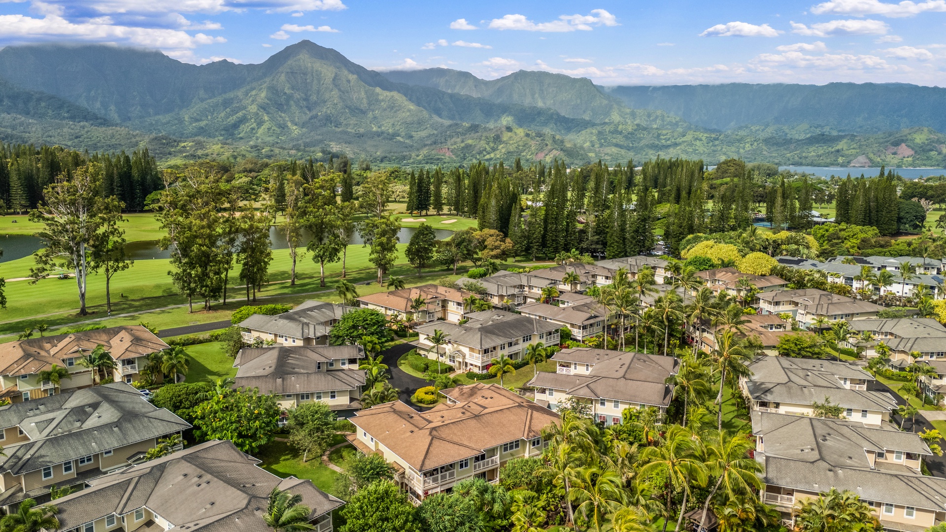 Princeville Vacation Rentals, Kaimana Villa - Stunning aerial view of the residential neighborhood surrounded by lush tropical mountains and golf course greens in this Hawaiian paradise.